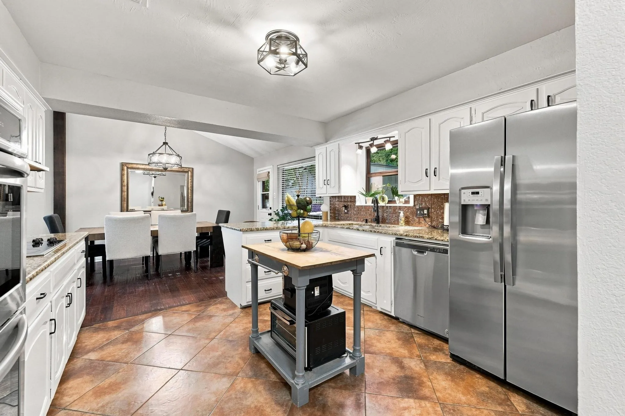 Kitchen featuring stainless steel appliances, white cabinetry, granite countertops, and tile flooring