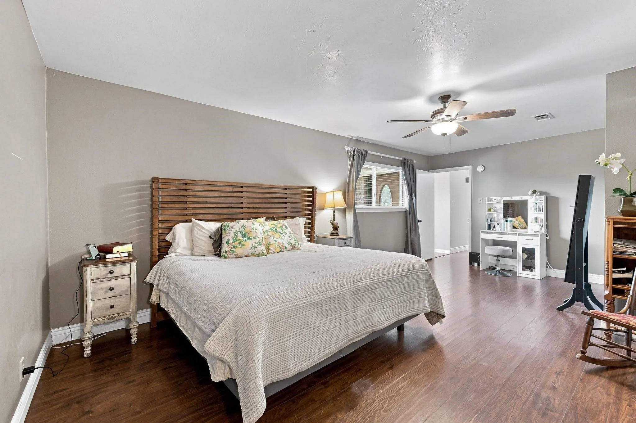 Spacious room featuring wood-finish flooring, a ceiling fan with integrated lighting, and neutral wall tones