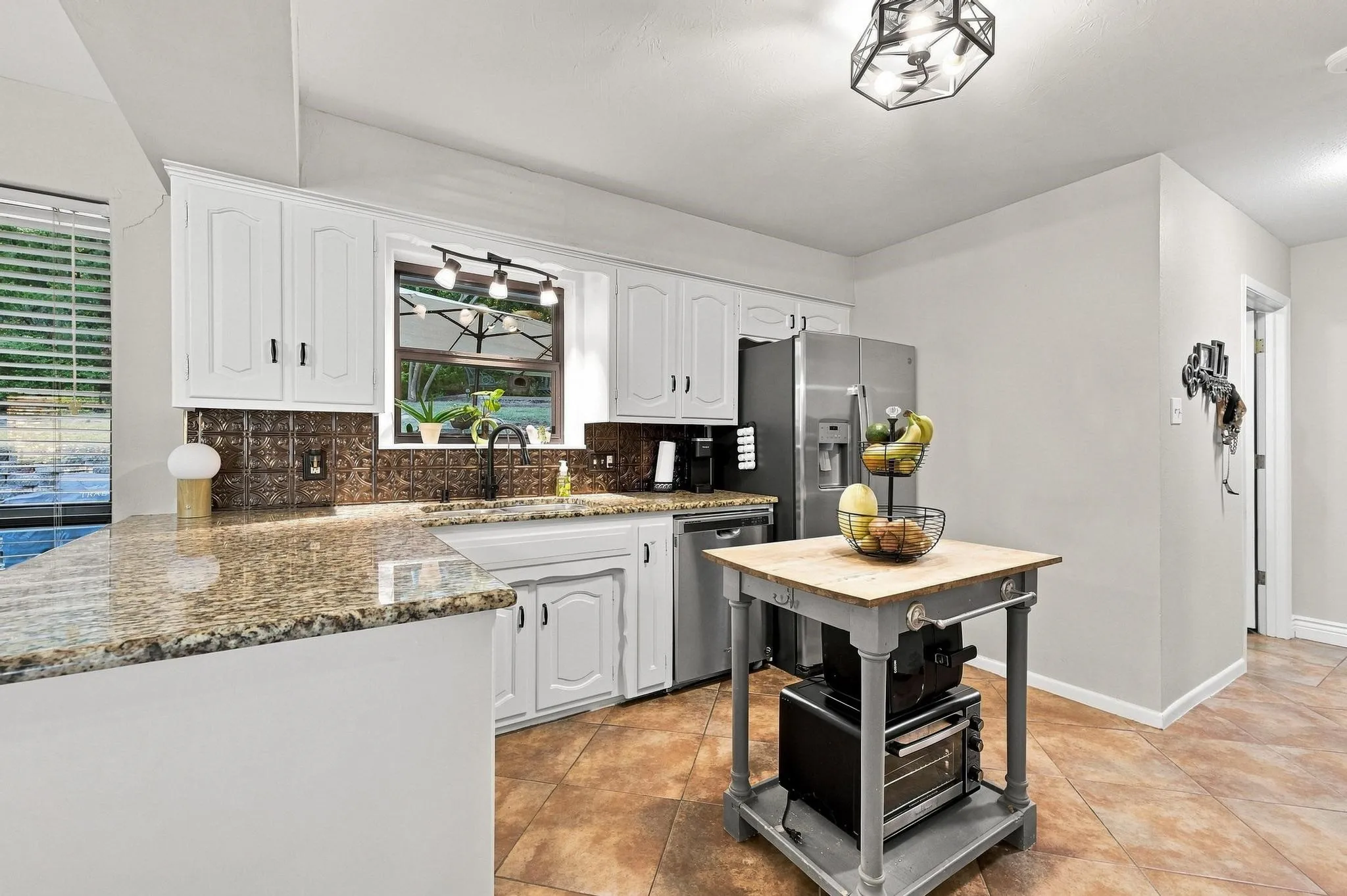 Kitchen featuring white cabinetry, granite countertops, a tiled backsplash, and stainless steel appliances