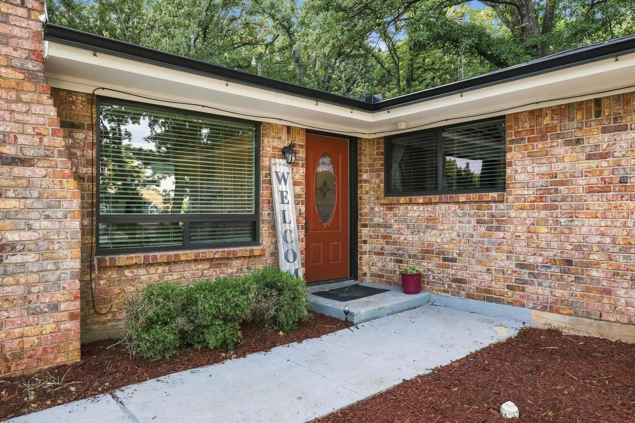Brick exterior with dark trim and an accent entry door