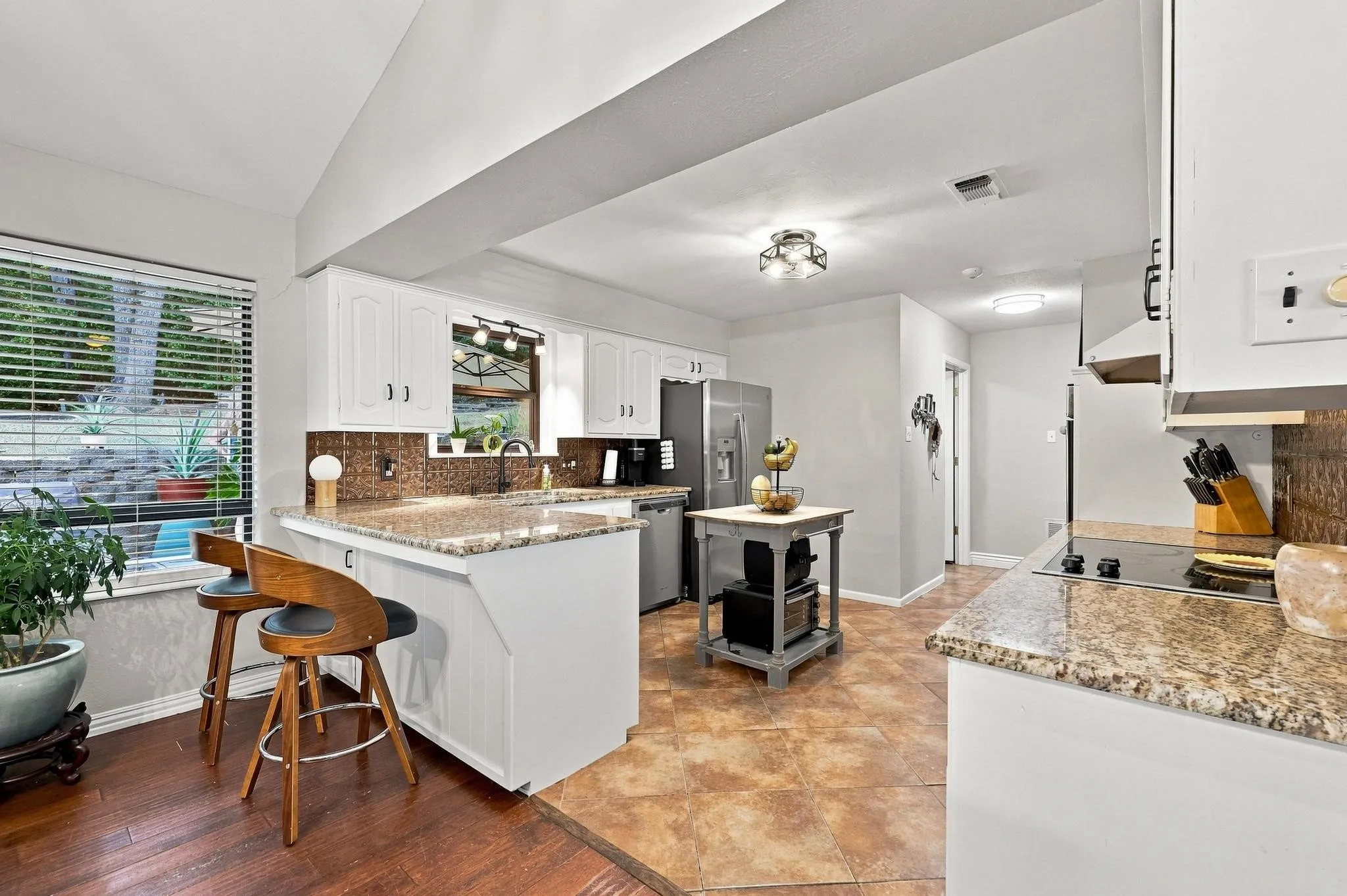 Kitchen featuring white cabinetry, stone-finish countertops, a tile backsplash, and a built-in cooktop