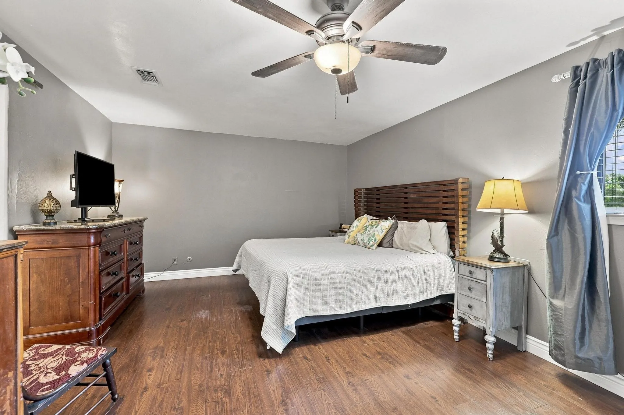 Wood-finish flooring, ceiling fan with integrated lighting, and a window with blinds