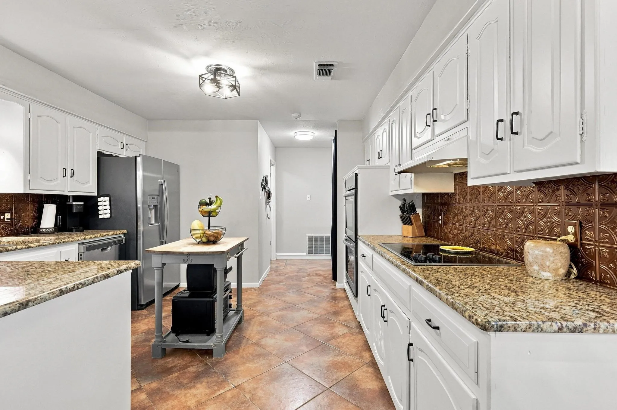 Kitchen featuring white cabinetry, stainless steel appliances, granite countertops, a decorative backsplash, and tiled flooring