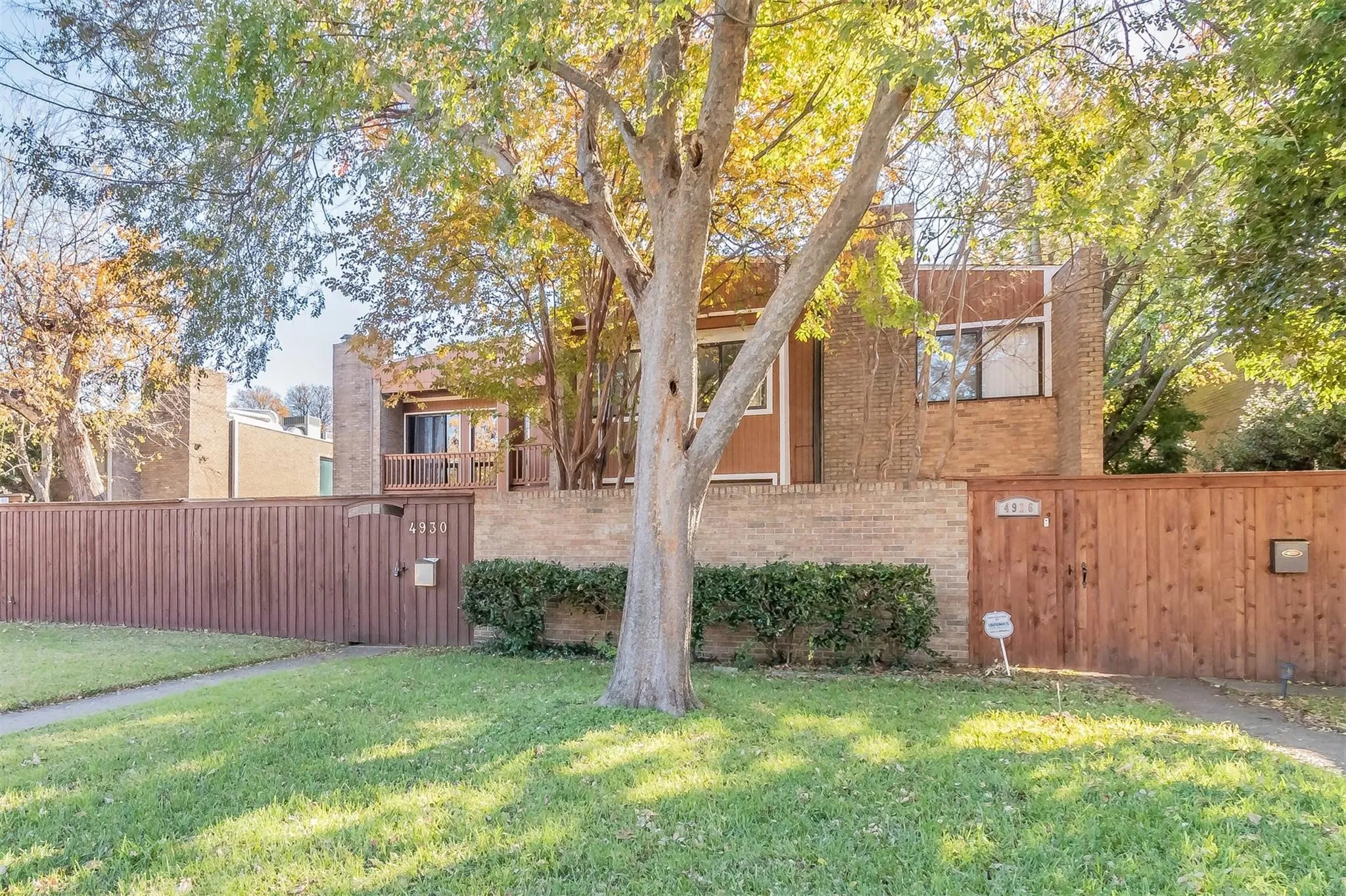Brick and wood-finish exterior with a wood privacy fence