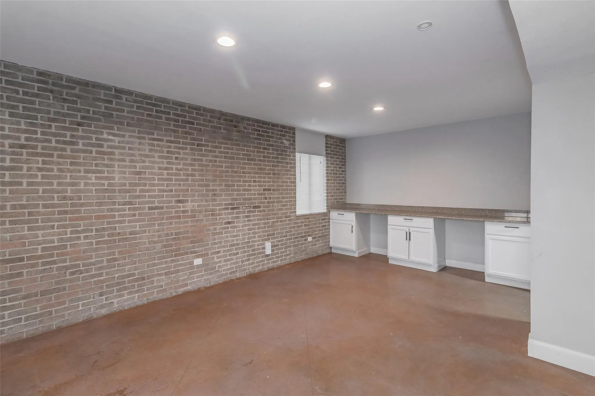 Exposed brick wall with built-in cabinetry, counter space, and recessed lighting