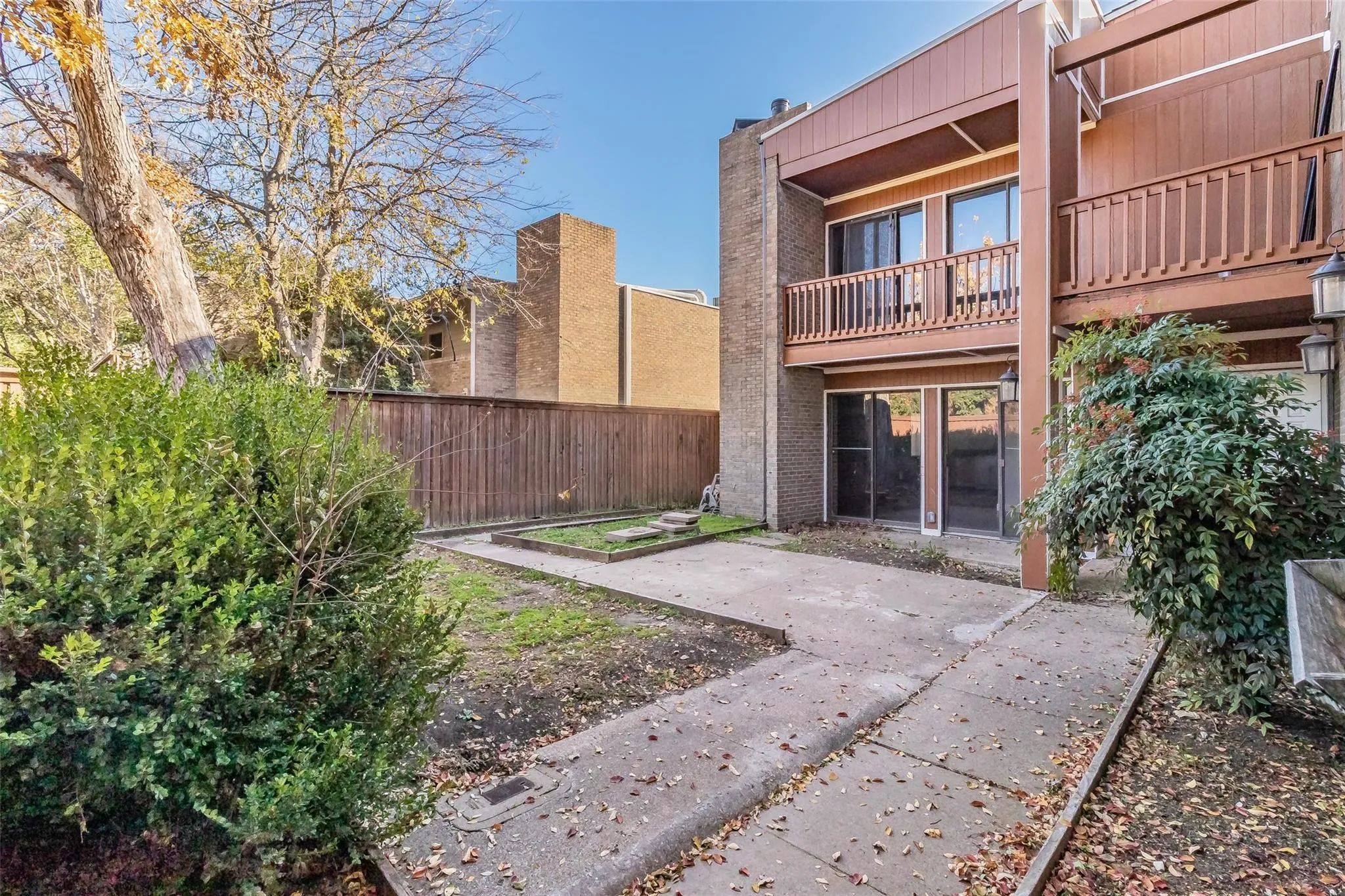 Concrete patio with integrated planting beds, wood fencing, and mature landscaping