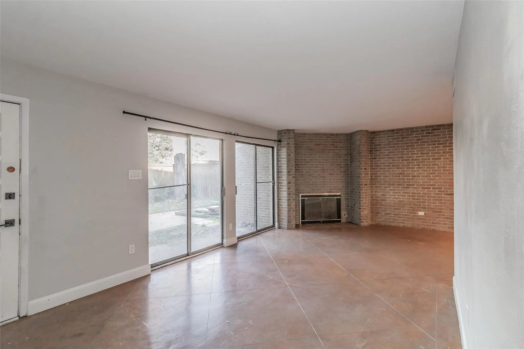 Spacious living area featuring a brick fireplace, sliding glass doors, and durable tile flooring