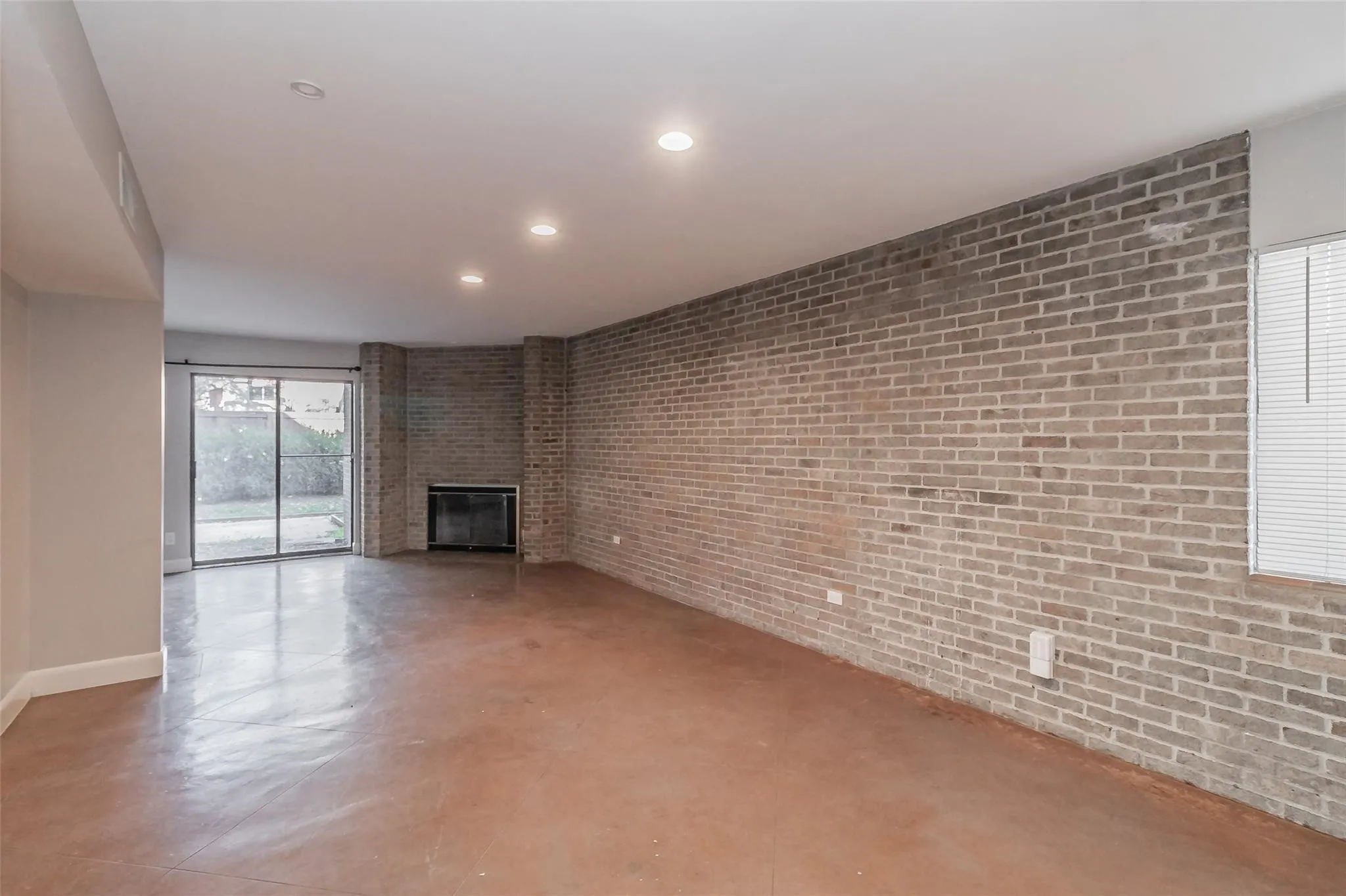 Exposed brick wall, recessed lighting, fireplace, sliding glass door, and hard-surface flooring