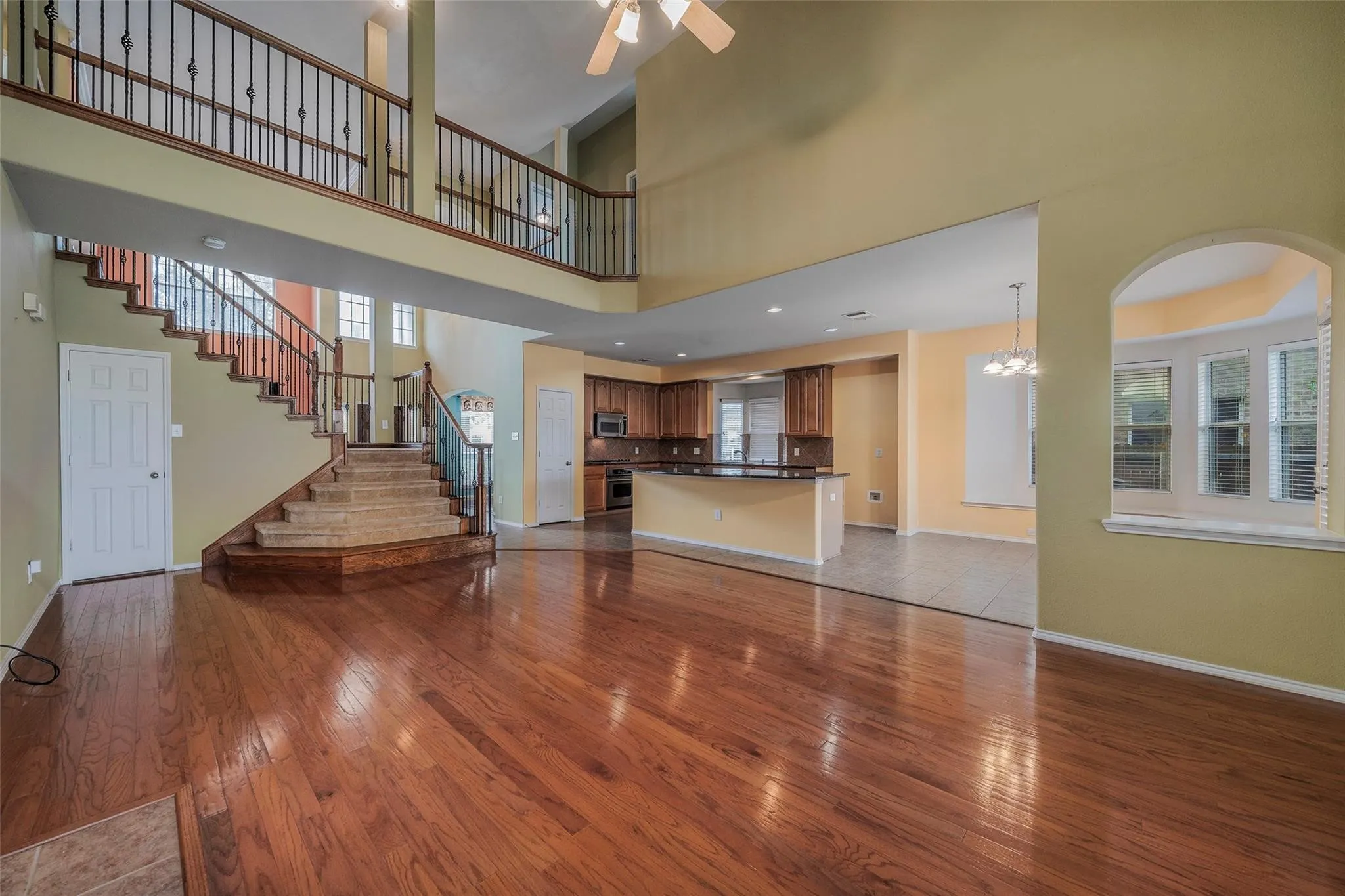 Unfurnished living room with hardwood / wood-style flooring, ceiling fan, and a towering ceiling