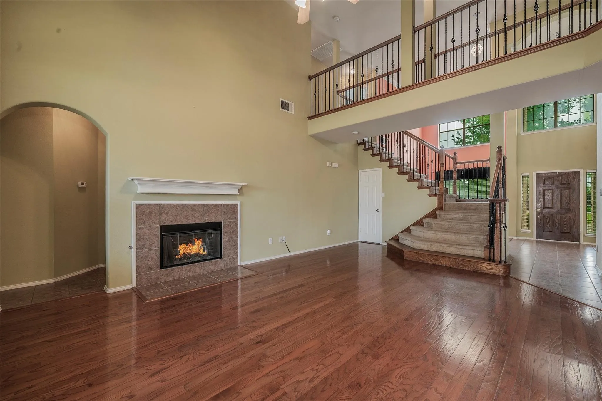 Living room featuring a tiled fireplace, a towering ceiling, and wood-type flooring