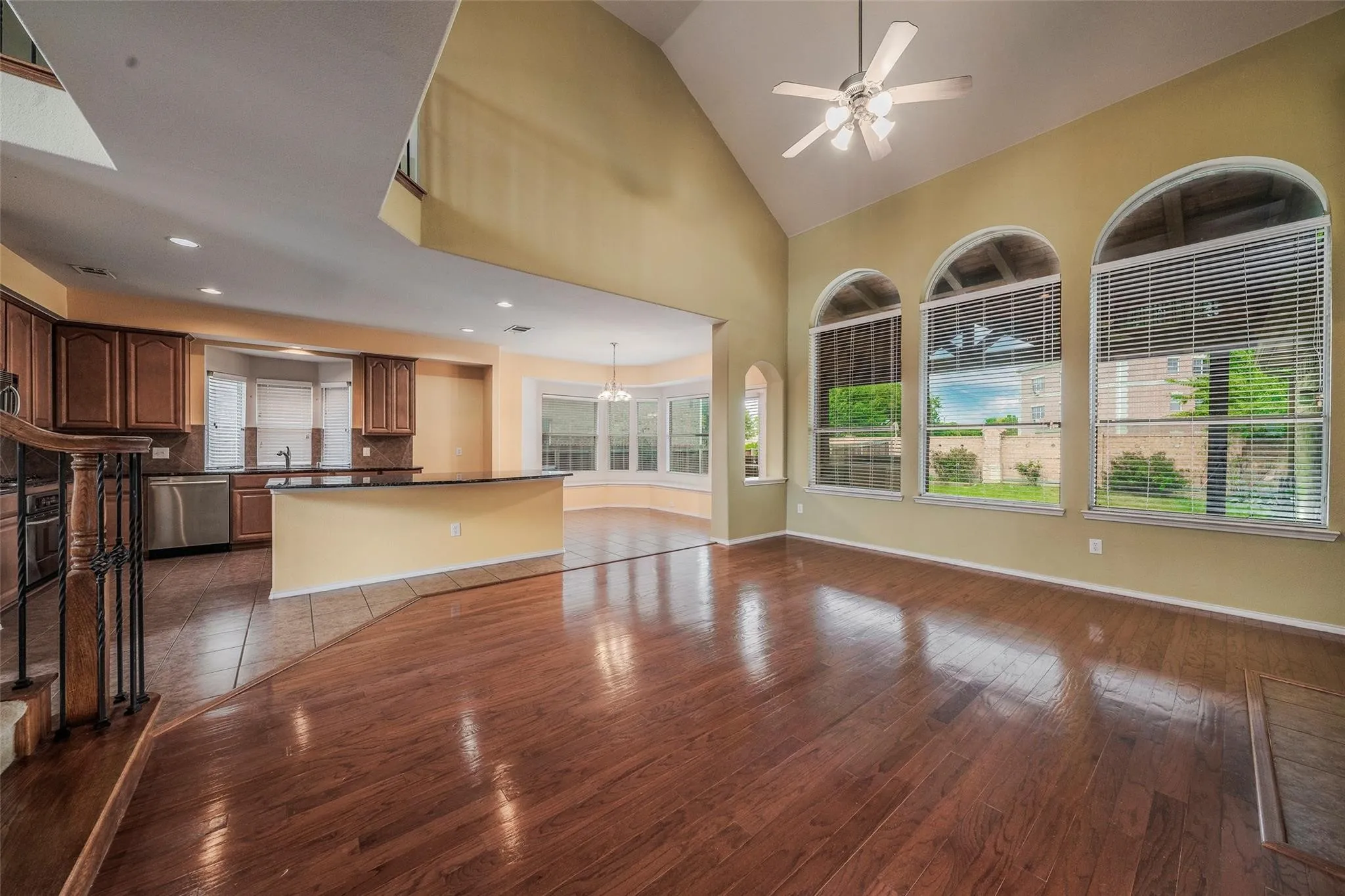 Unfurnished living room with ceiling fan with notable chandelier, dark hardwood / wood-style flooring, high vaulted ceiling, and sink