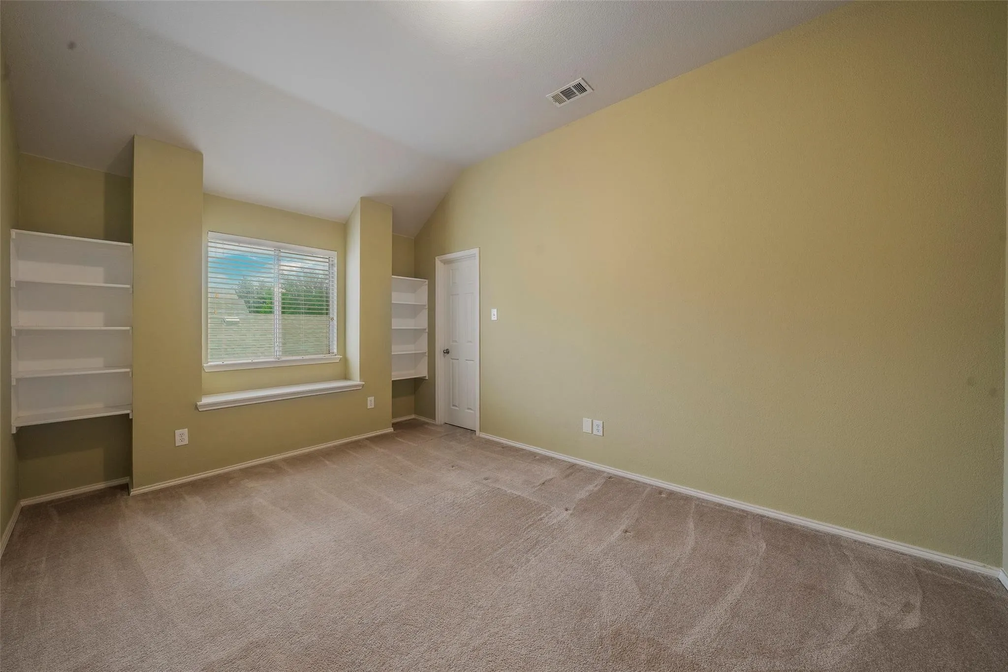 Unfurnished bedroom featuring light colored carpet and lofted ceiling