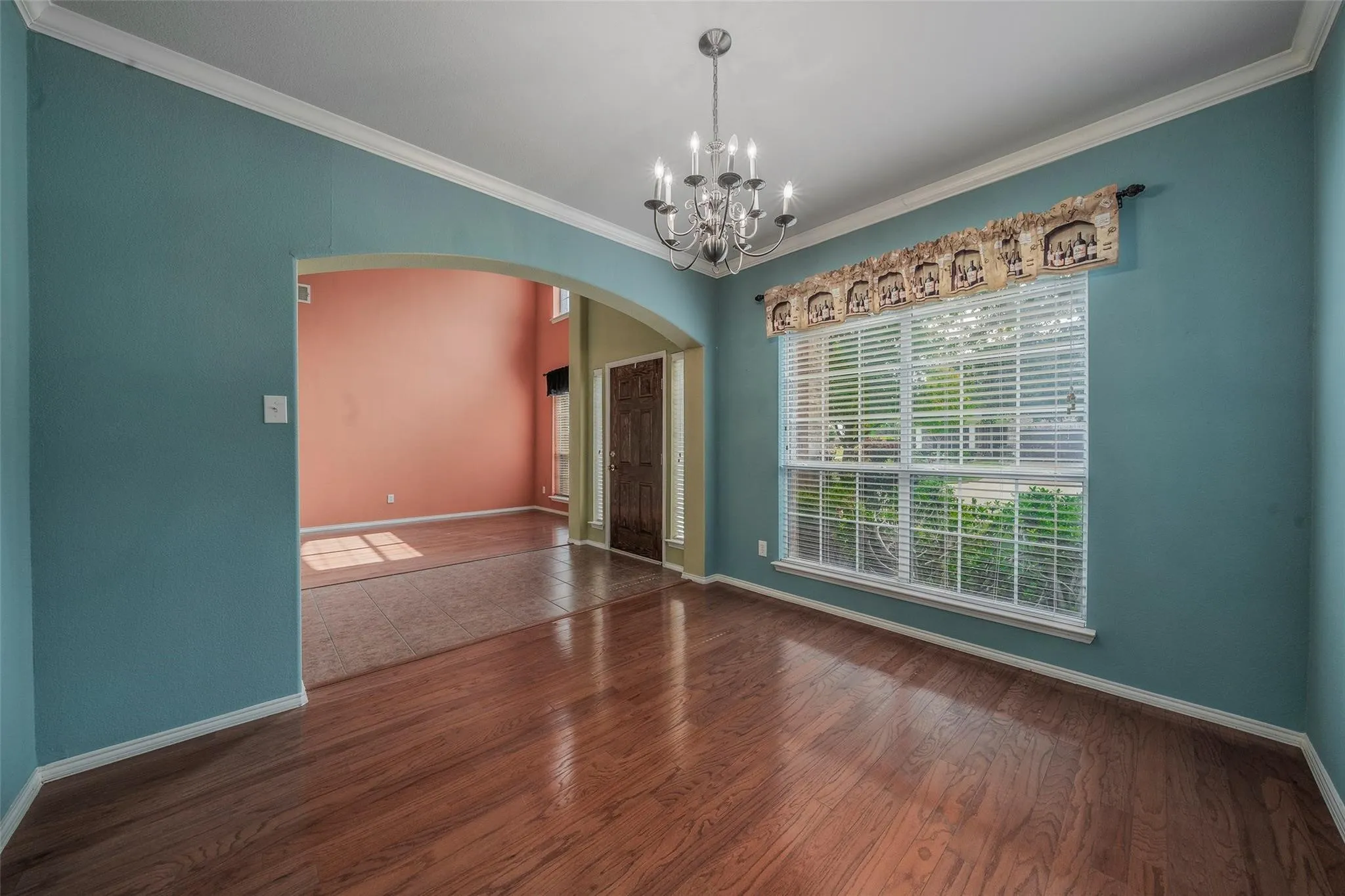 Spare room featuring dark hardwood / wood-style flooring, an inviting chandelier, and crown molding