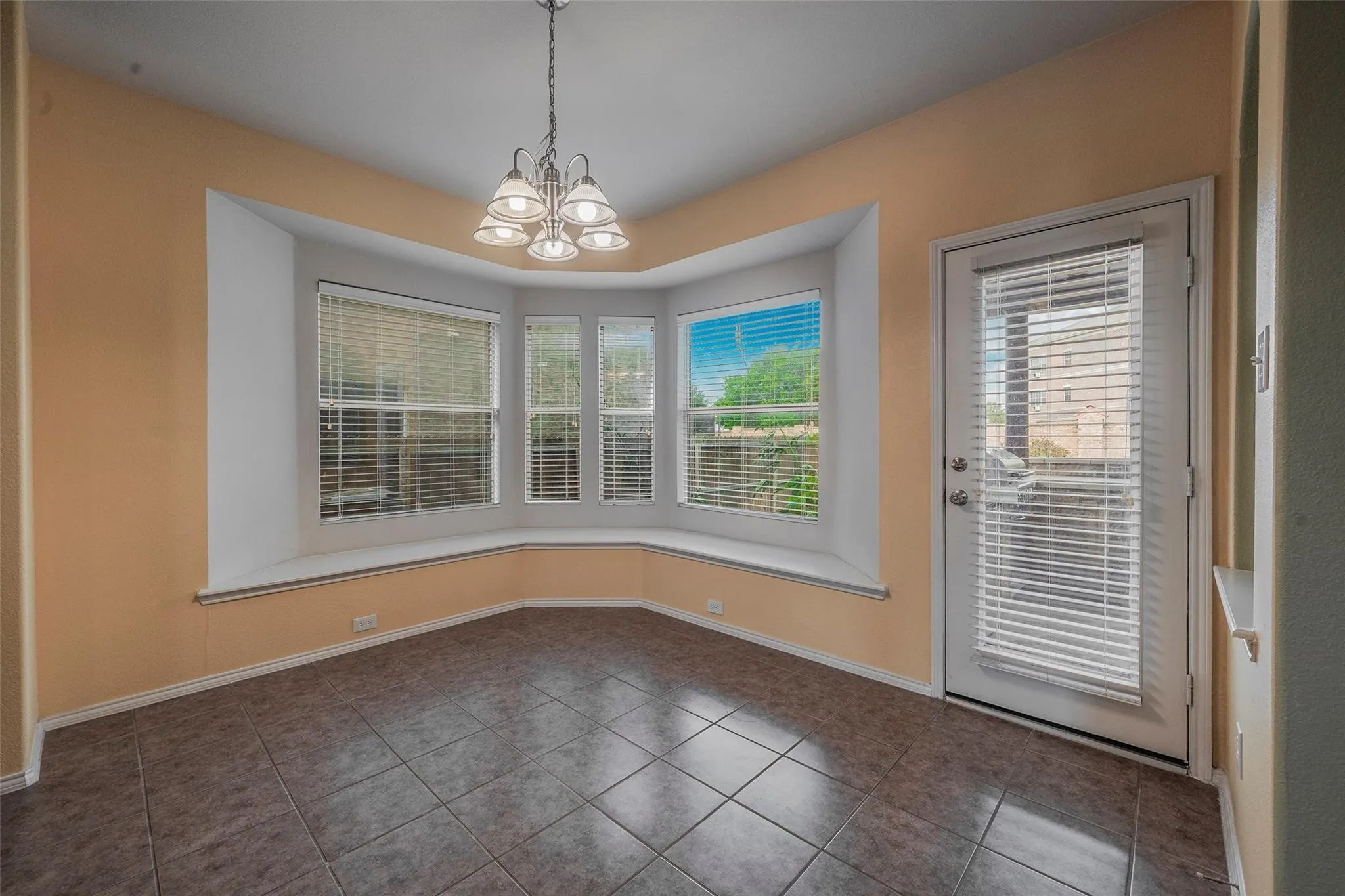 Unfurnished dining area with a chandelier, dark tile patterned flooring, and a wealth of natural light