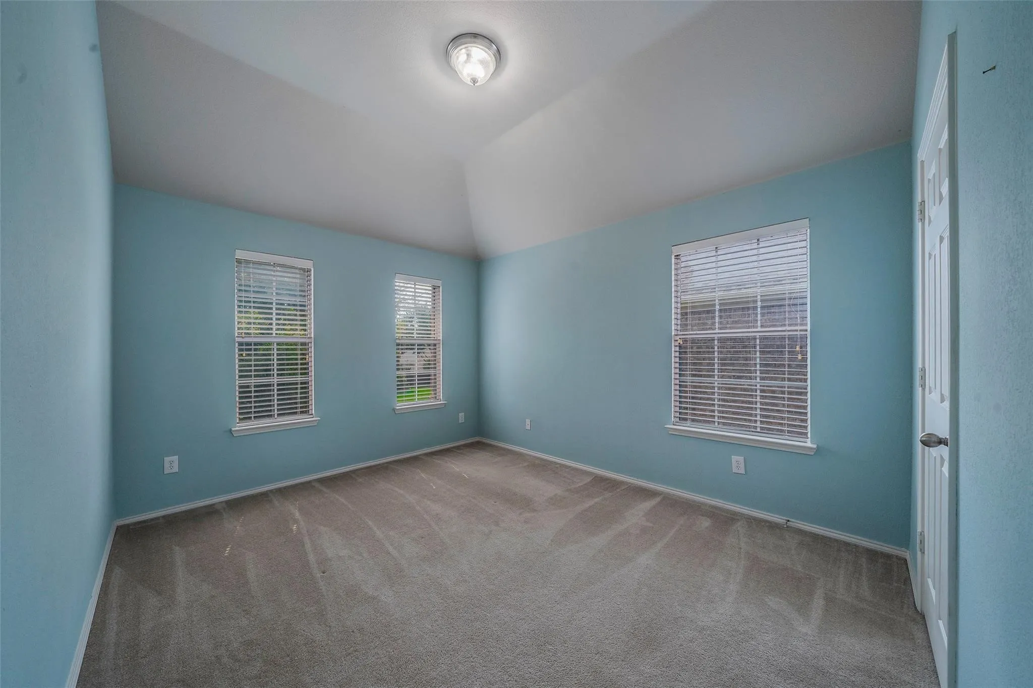 Unfurnished room featuring lofted ceiling and light carpet