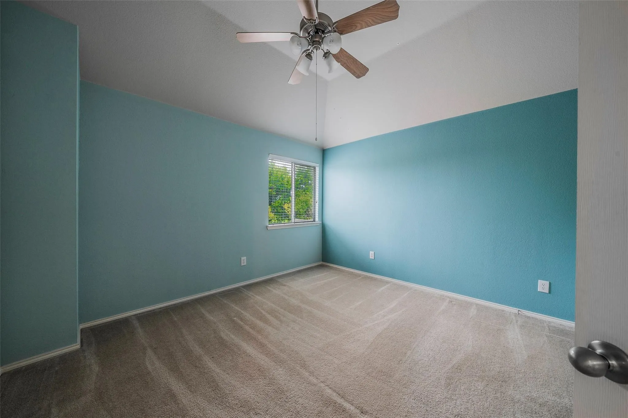 Empty room featuring carpet flooring, ceiling fan, and lofted ceiling