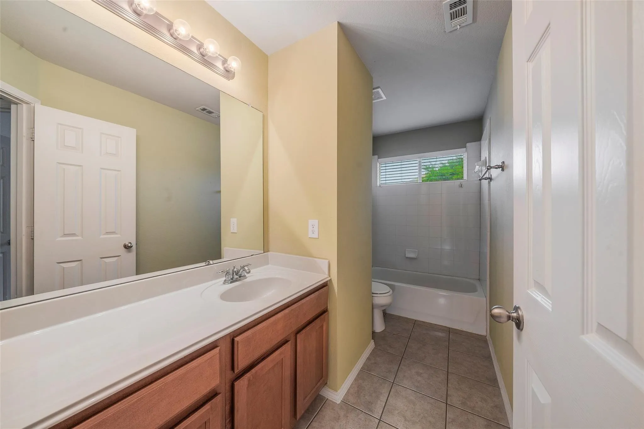 Full bathroom with tile patterned flooring, vanity, toilet, and tiled shower / bath combo