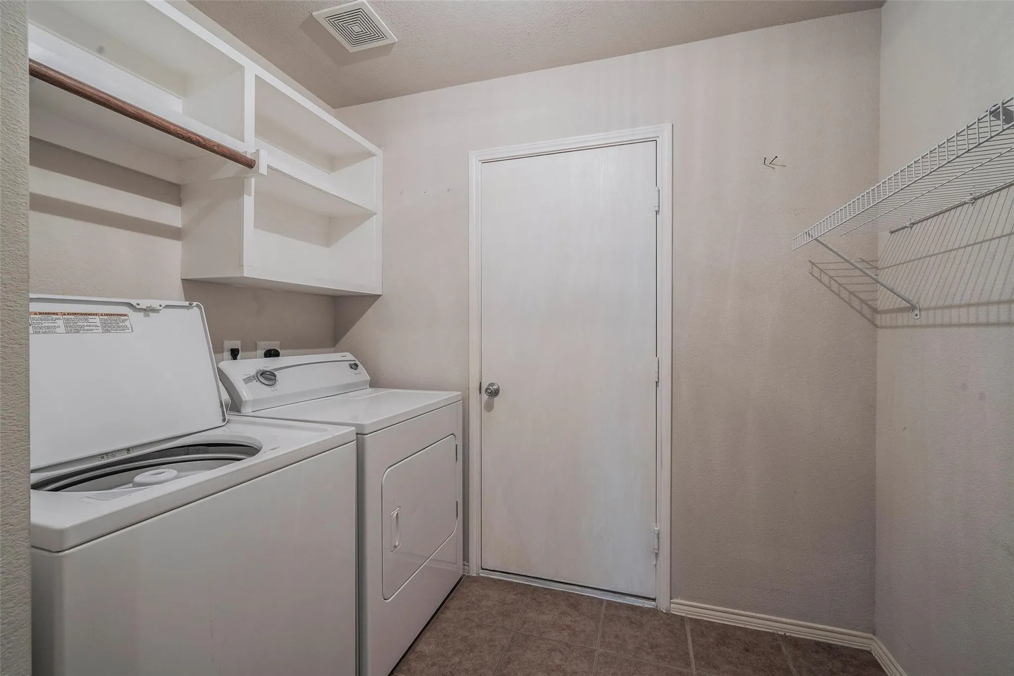 Washroom with independent washer and dryer and dark tile patterned flooring