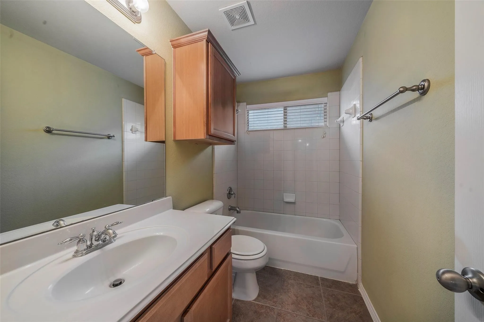 Full bathroom featuring tile patterned flooring, vanity, tiled shower / bath combo, and toilet