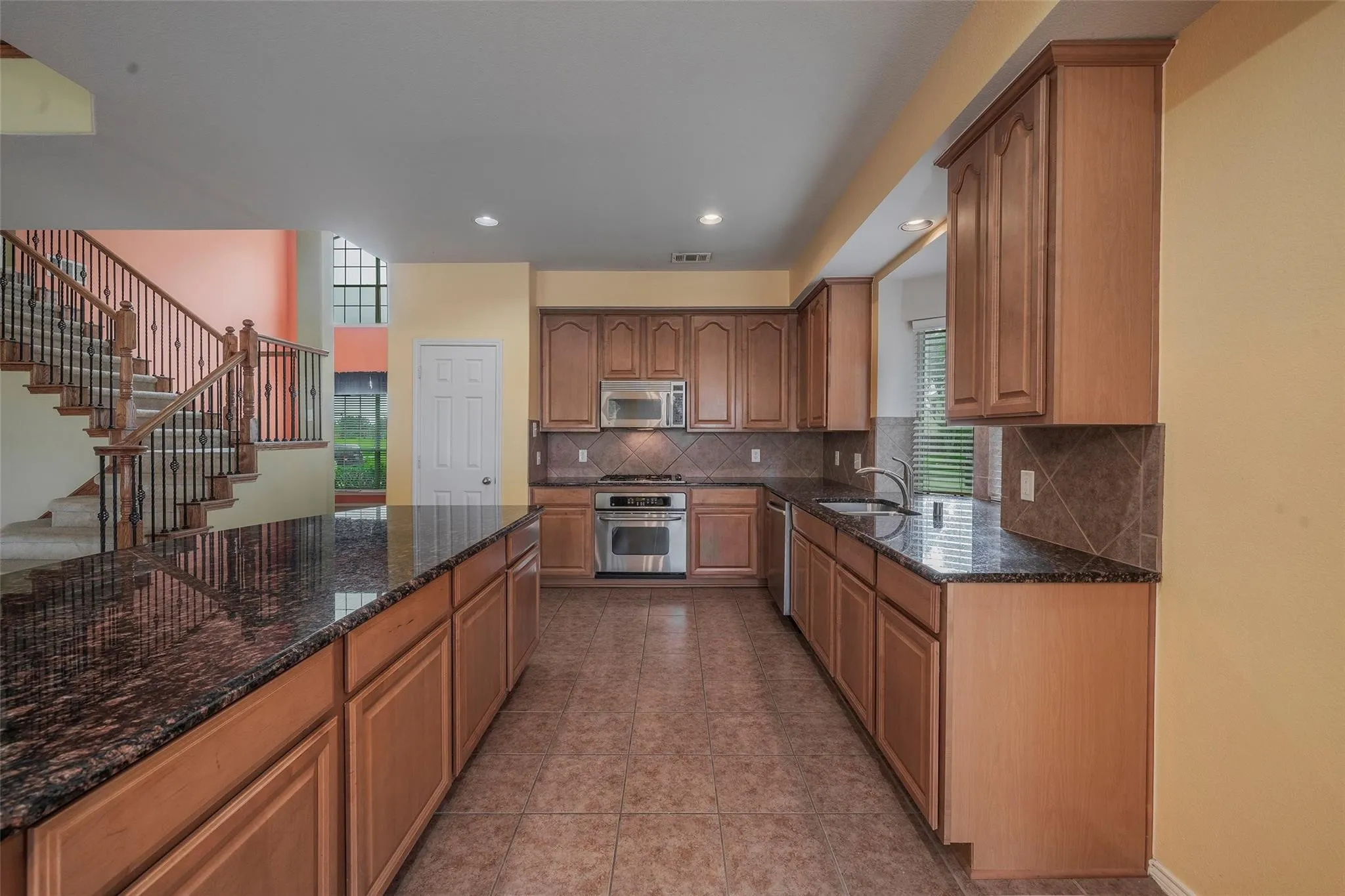 Kitchen with backsplash, light tile patterned flooring, sink, and stainless steel appliances