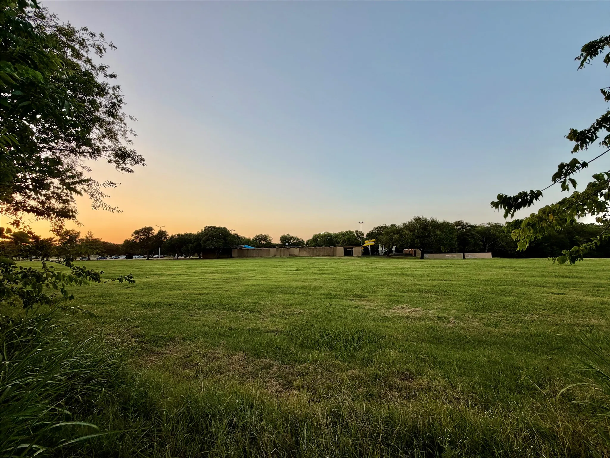 Expansive green space featuring a large grassy area and distant trees