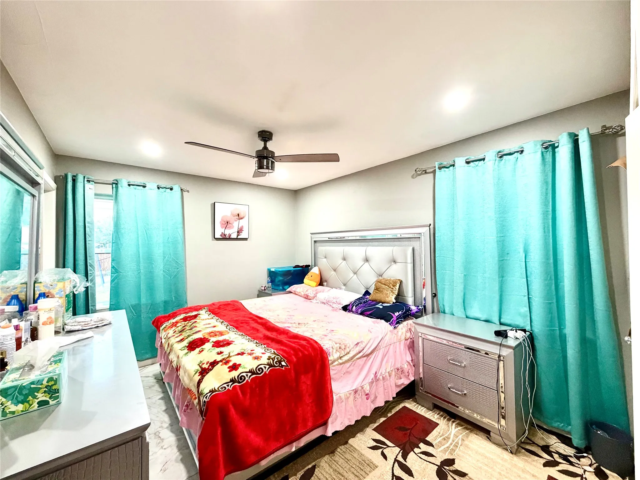 Bedroom featuring a ceiling fan with integrated lighting, recessed ceiling lights, and two windows with curtain rods