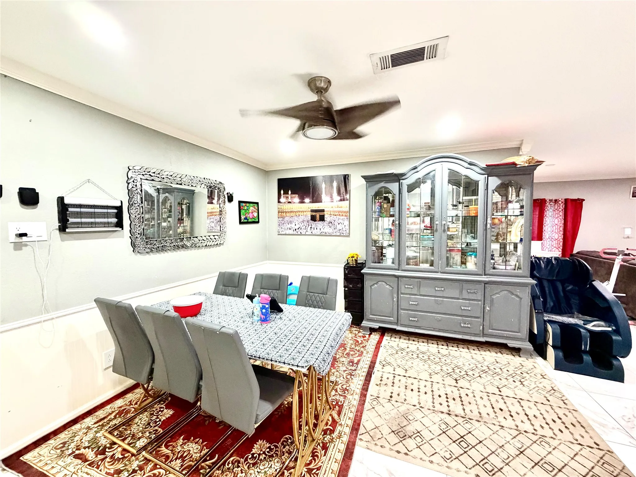 Dining area featuring crown molding, a ceiling fan, and a built-in display cabinet with glass doors