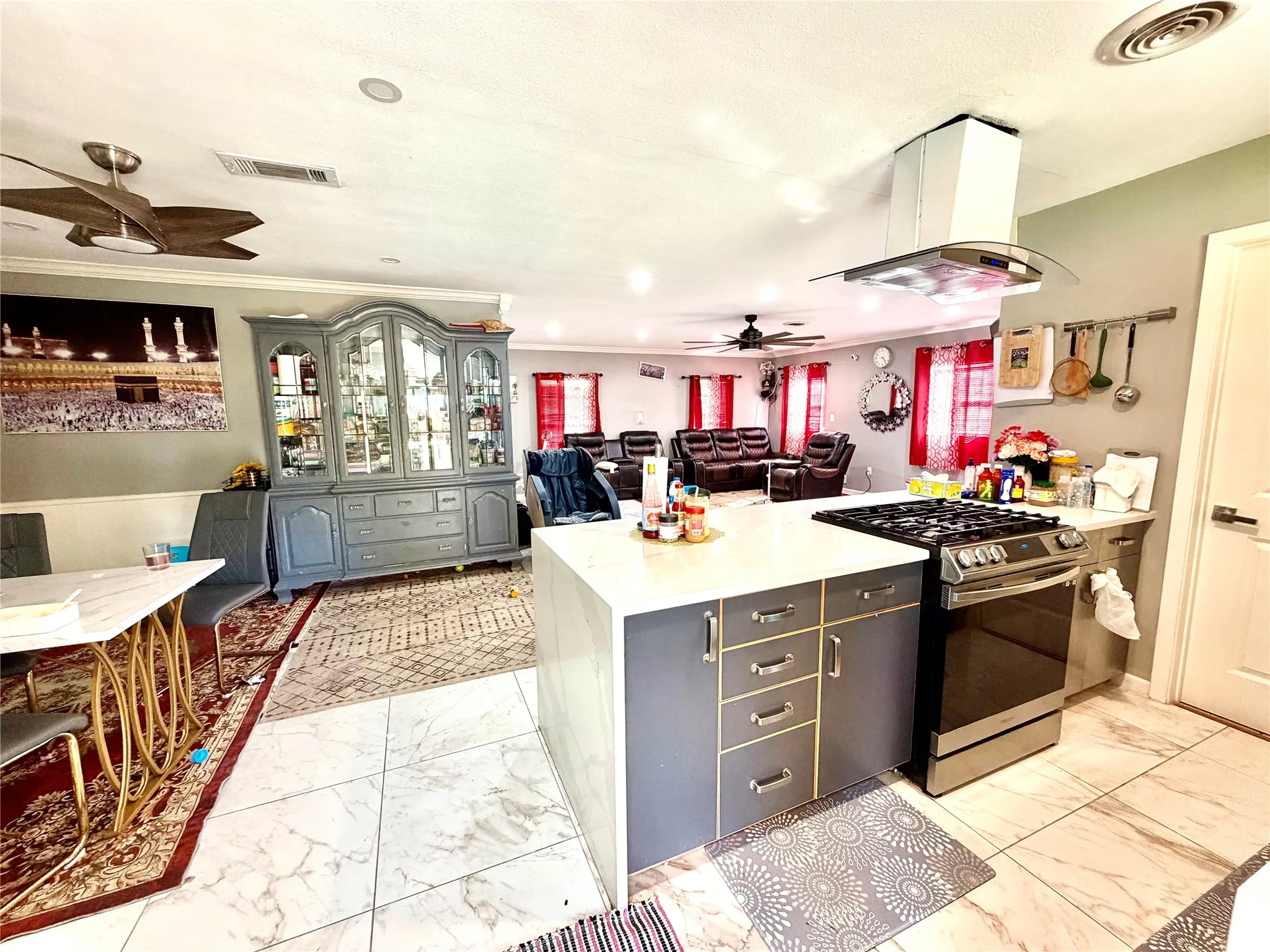 Open-concept kitchen featuring an island with built-in storage, stainless steel range with a ventilation hood, and tile flooring