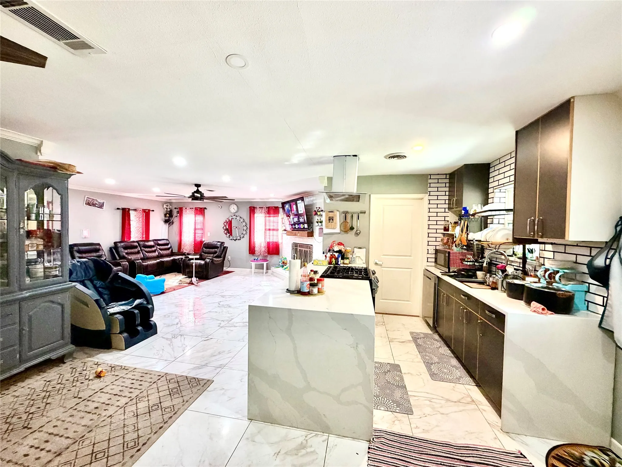 Open-concept layout featuring a kitchen island with a waterfall edge, tile flooring, and recessed lighting