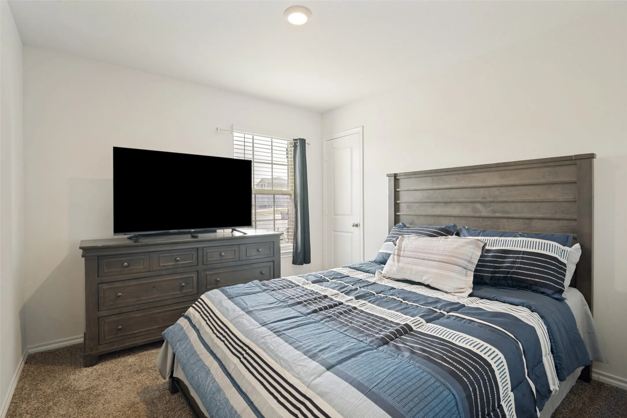 Recessed ceiling light, carpet flooring, window with blinds, interior door