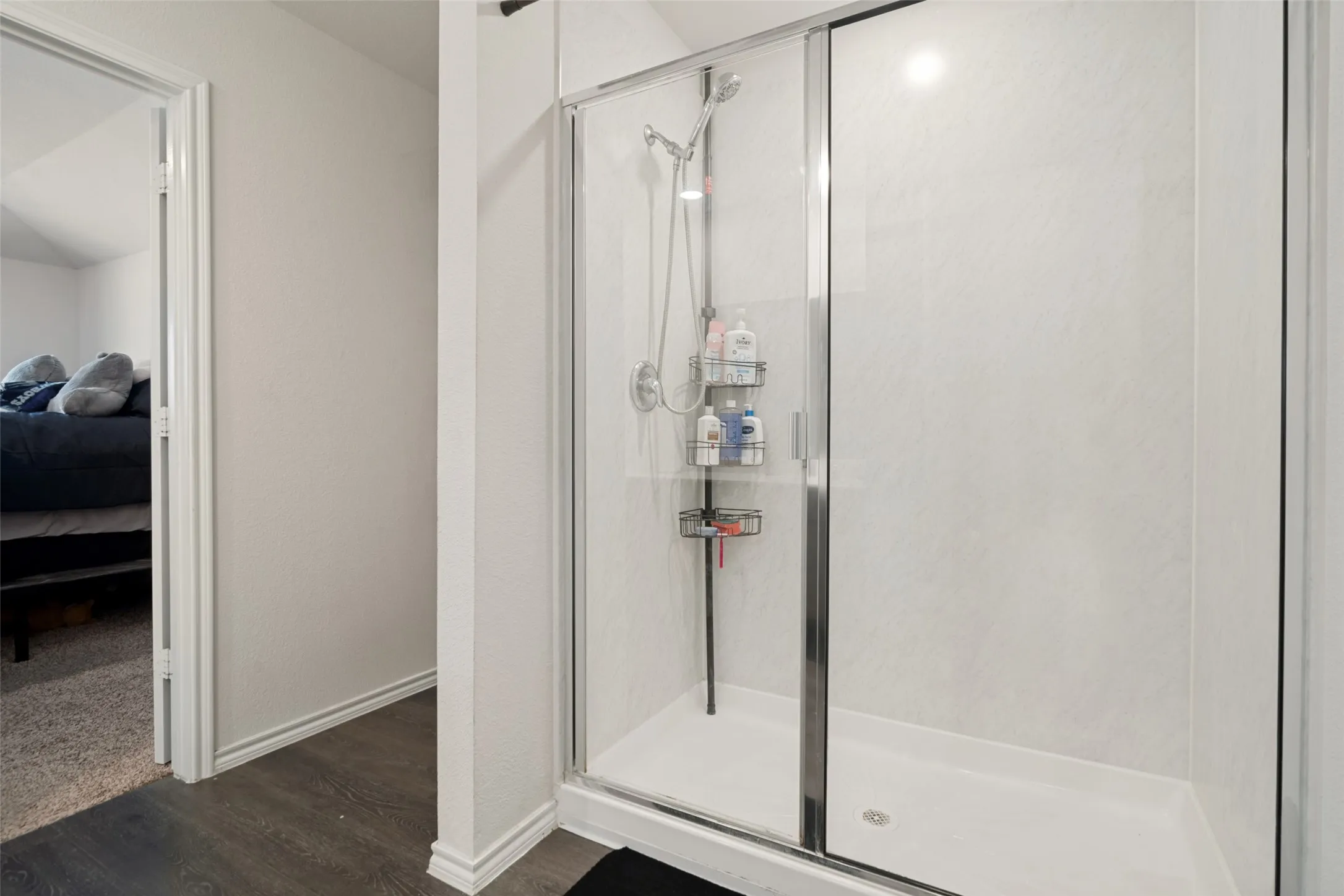 Shower enclosure with clear glass doors, white shower base, and white textured wall panels