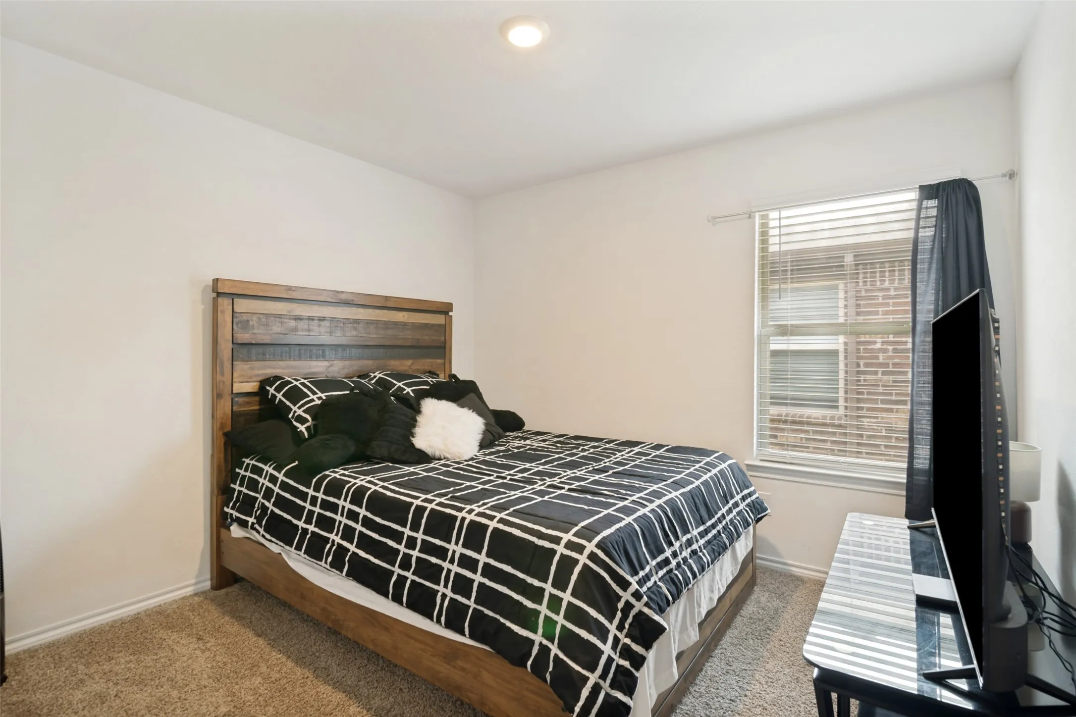 Recessed ceiling light, neutral wall paint, wood-finish flooring, window with blinds