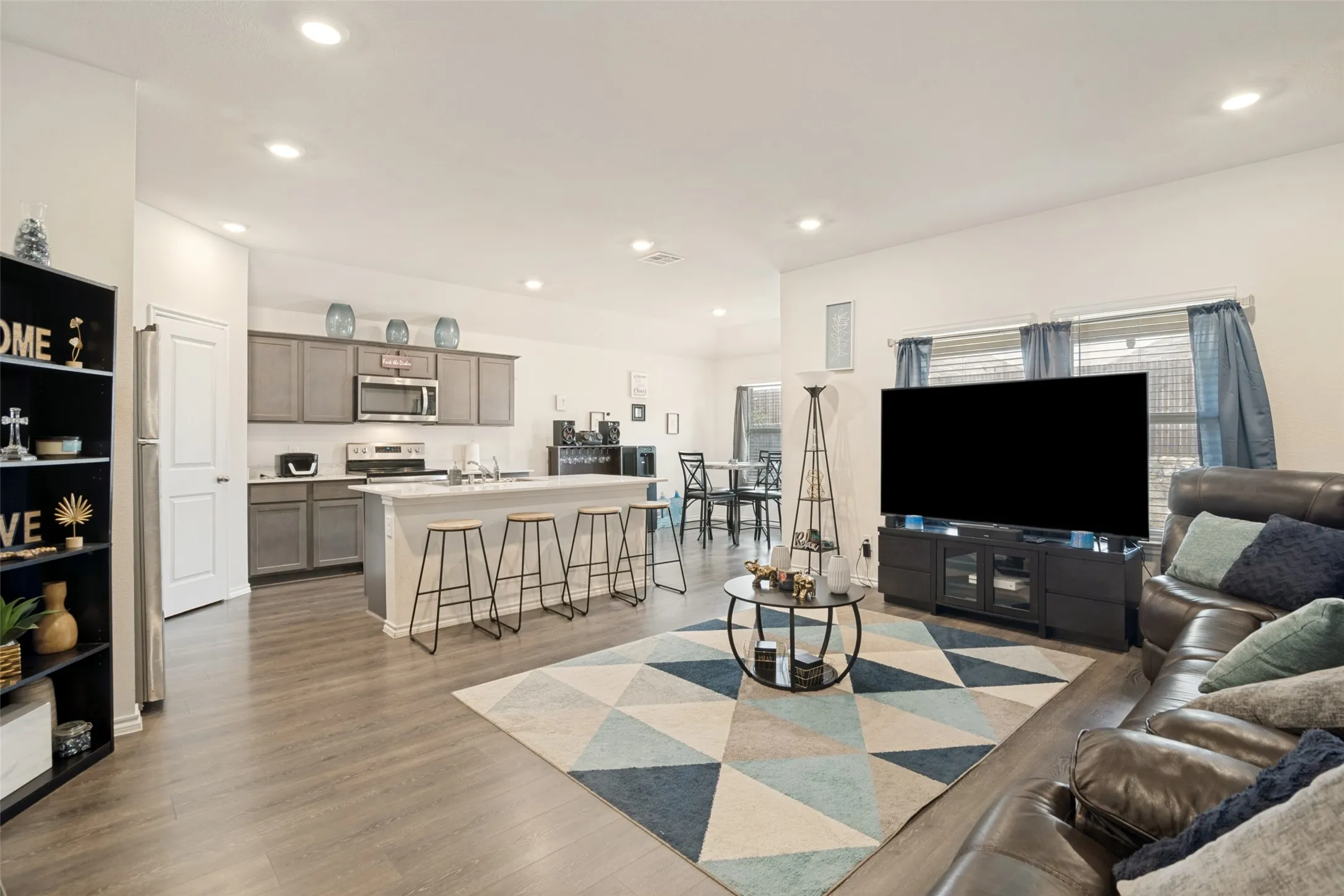 Open-concept living space with wood-finish flooring, recessed lighting, and a white kitchen island