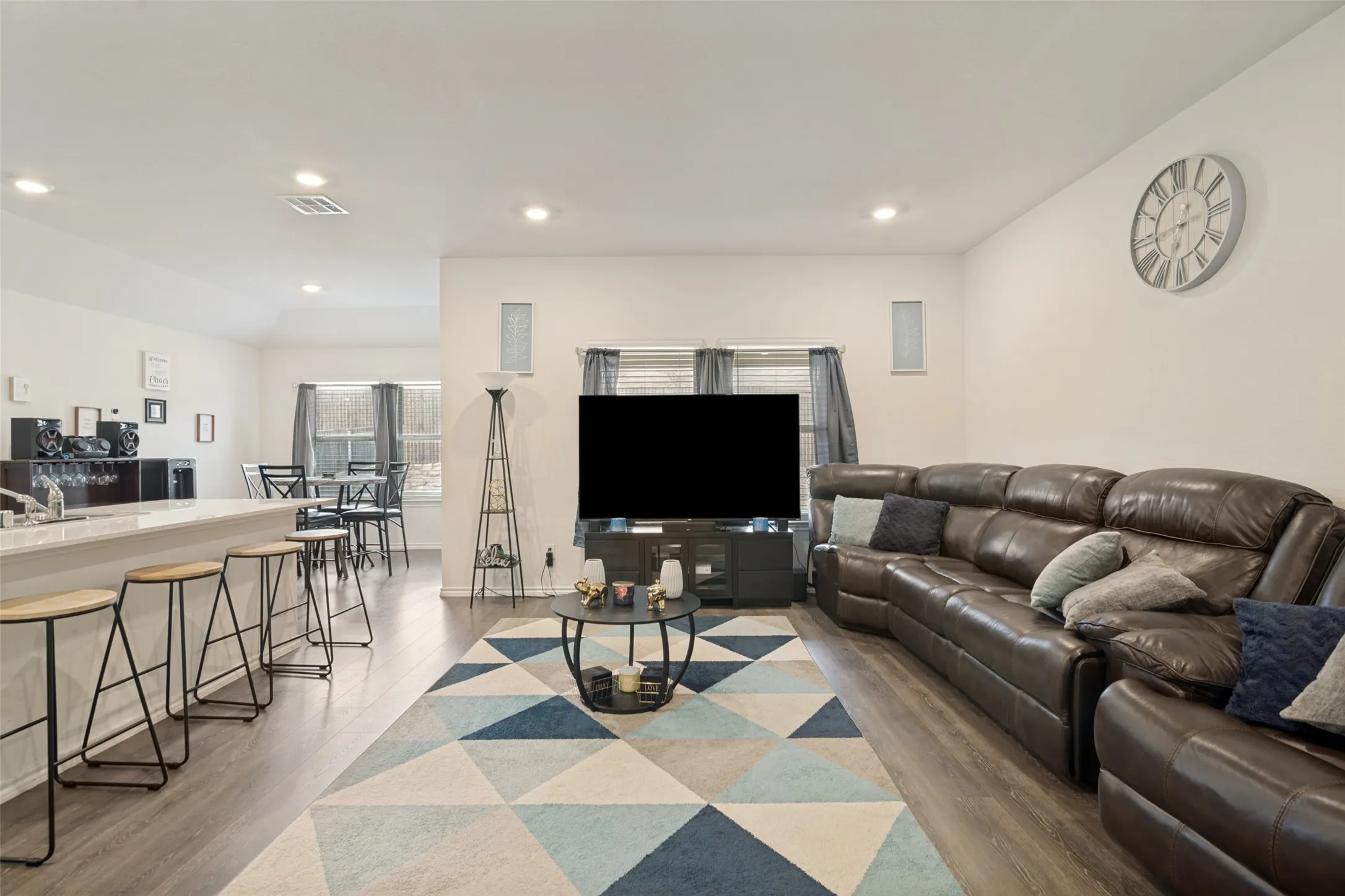 Open concept living area featuring wood-finish flooring, recessed lighting, and a white countertop breakfast bar