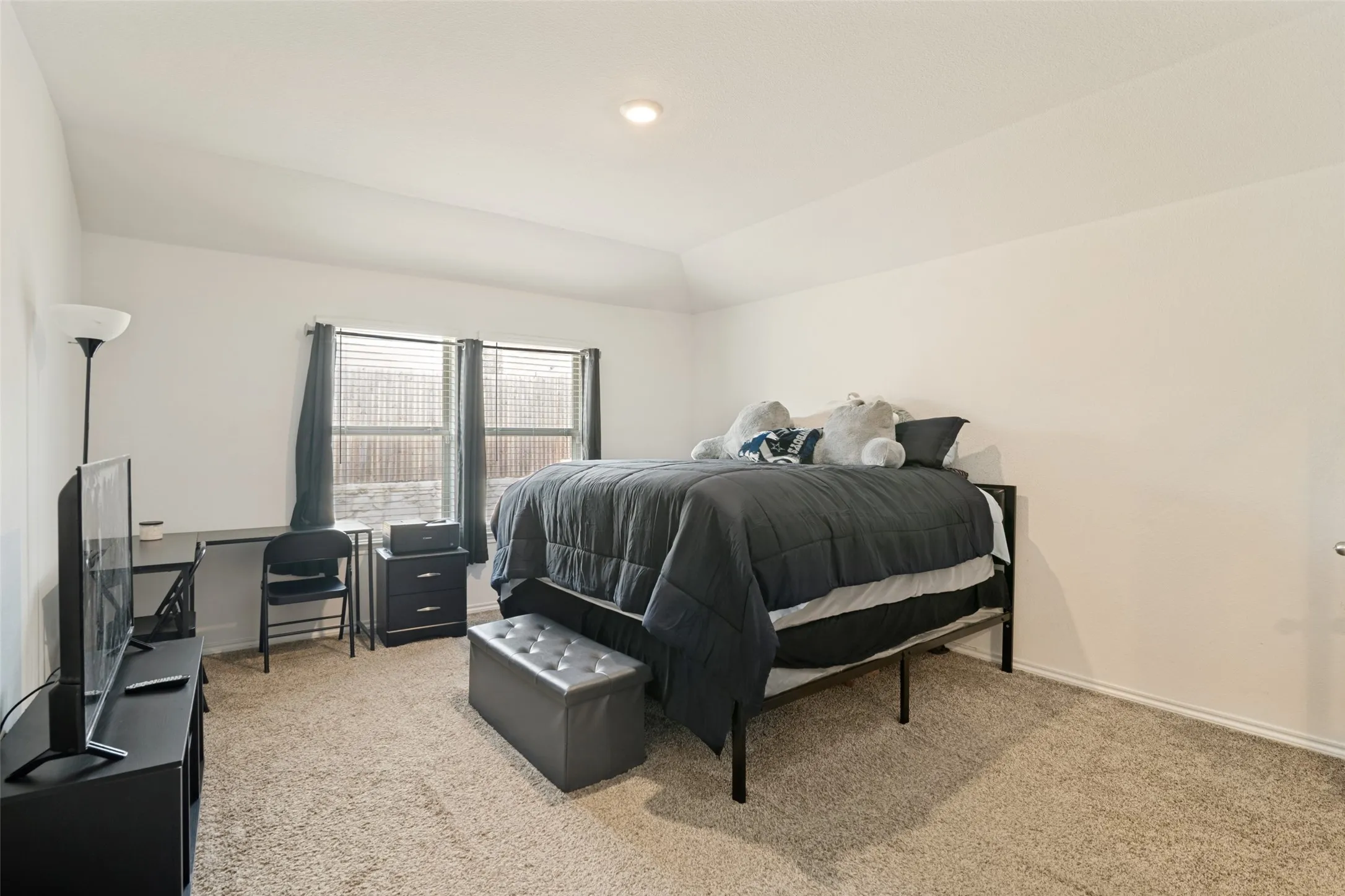 Neutral tone wall finishes, carpeting, and two windows with blinds