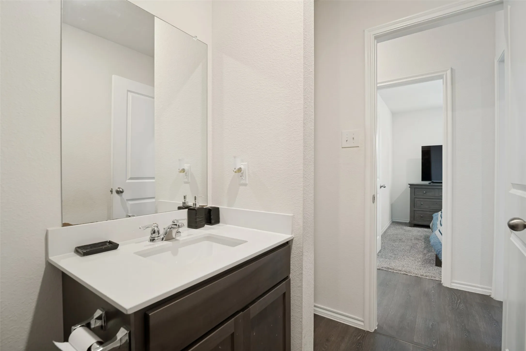 White vanity with an integrated sink and chrome faucet, set against a full-width wall mirror