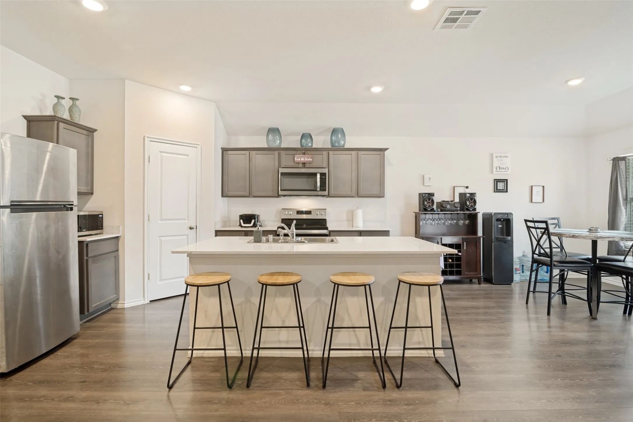 Kitchen with a central island, stainless steel appliances, recessed lighting, wood-finish flooring, and grey cabinetry