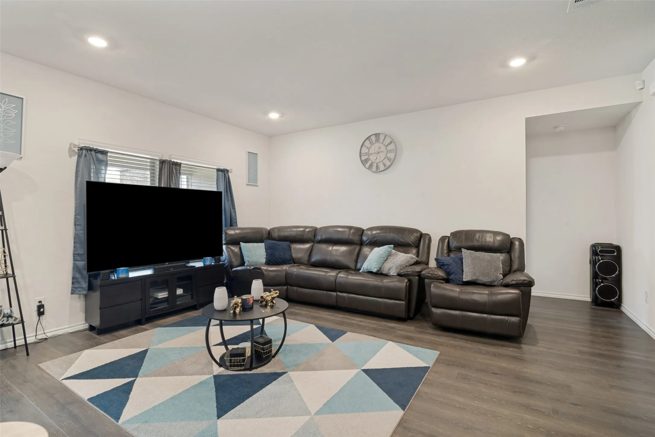Recessed lighting, wood-finish flooring, and a window with blinds provide a bright and inviting atmosphere