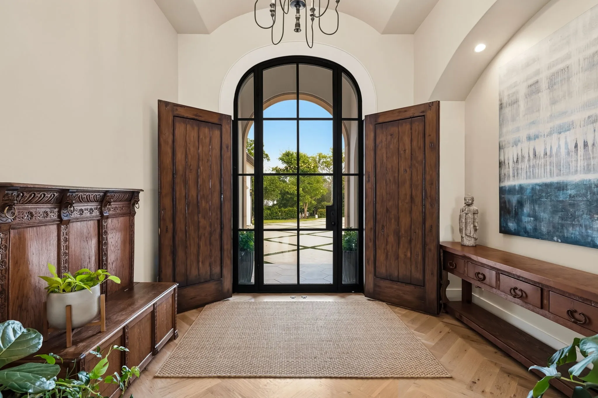 Arched entryway with a black steel-framed glass door and side panels, flanked by two solid wood doors