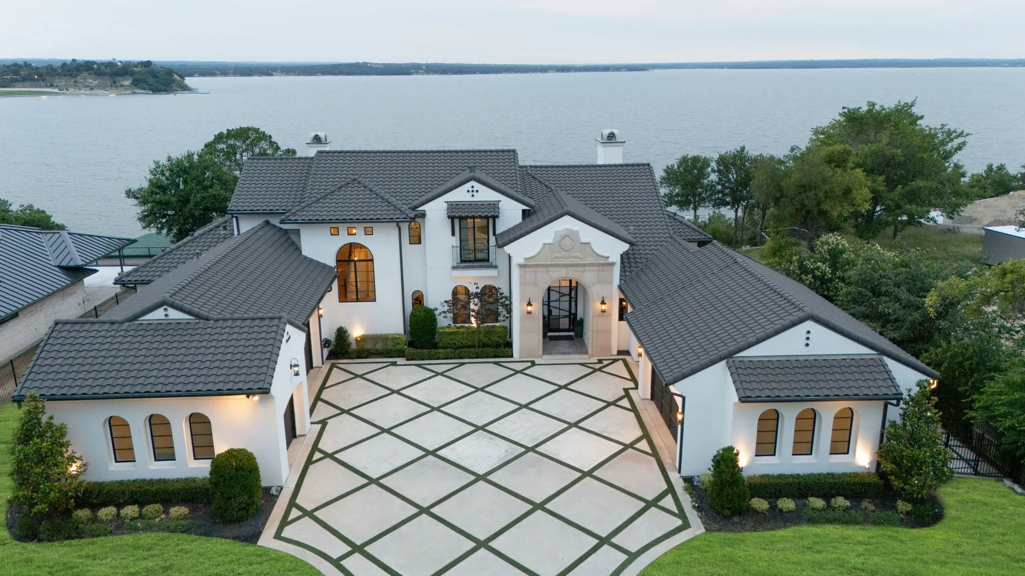 Mediterranean-style exterior with white stucco, dark tile roofing, and a patterned paver driveway