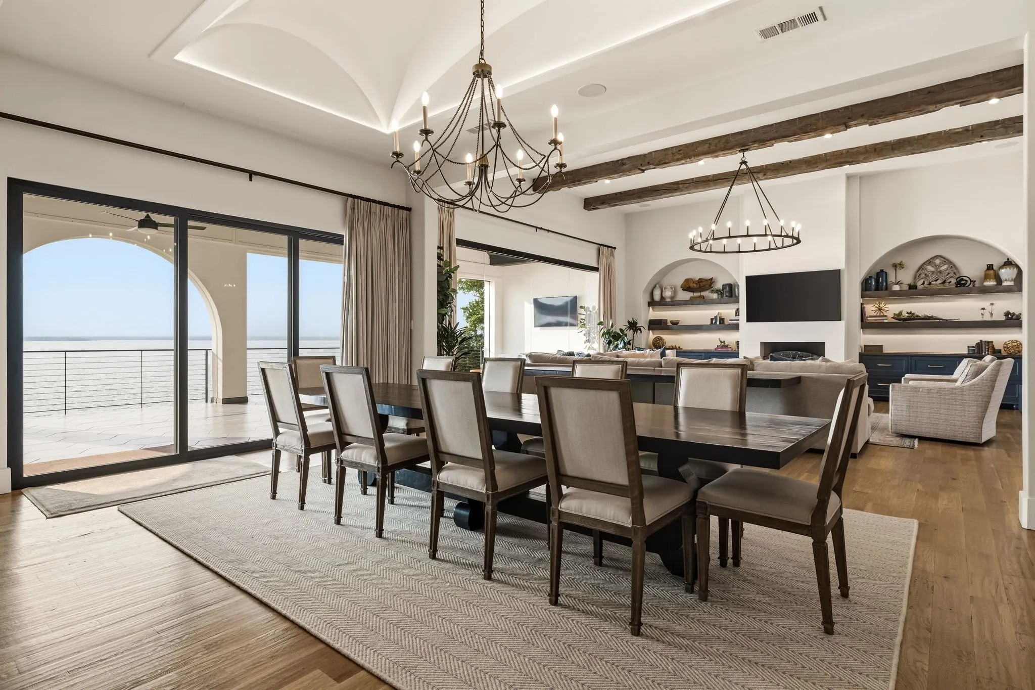Hardwood flooring, vaulted ceiling, exposed wood beams, sliding glass doors, built-in shelving with integrated lighting