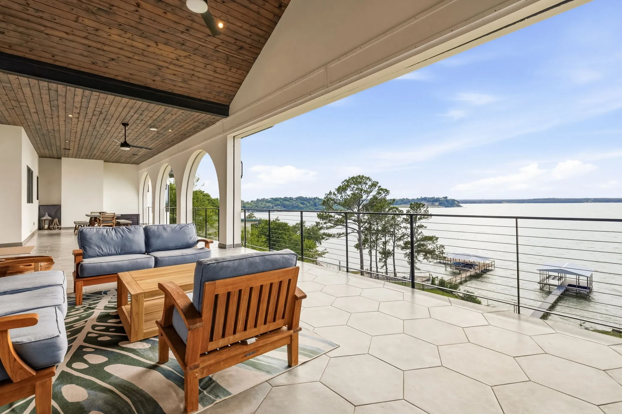 Expansive covered patio with a vaulted wood-paneled ceiling, hexagonal tile flooring, and a cable railing system