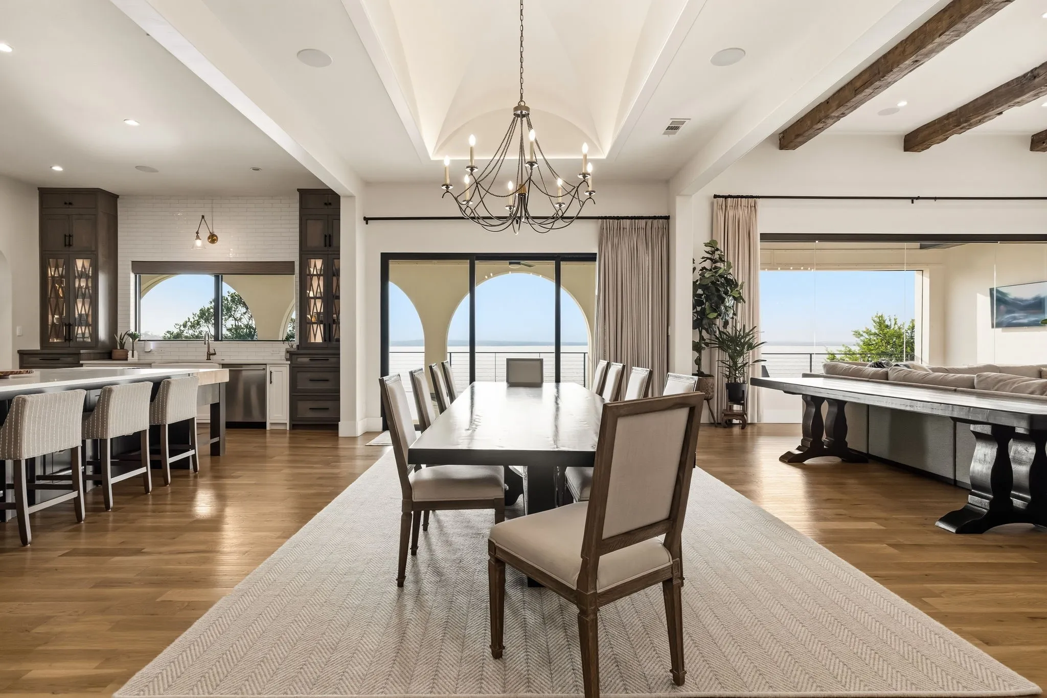 Expansive open-concept interior featuring light wood-finish flooring, a vaulted ceiling, and exposed wood beams