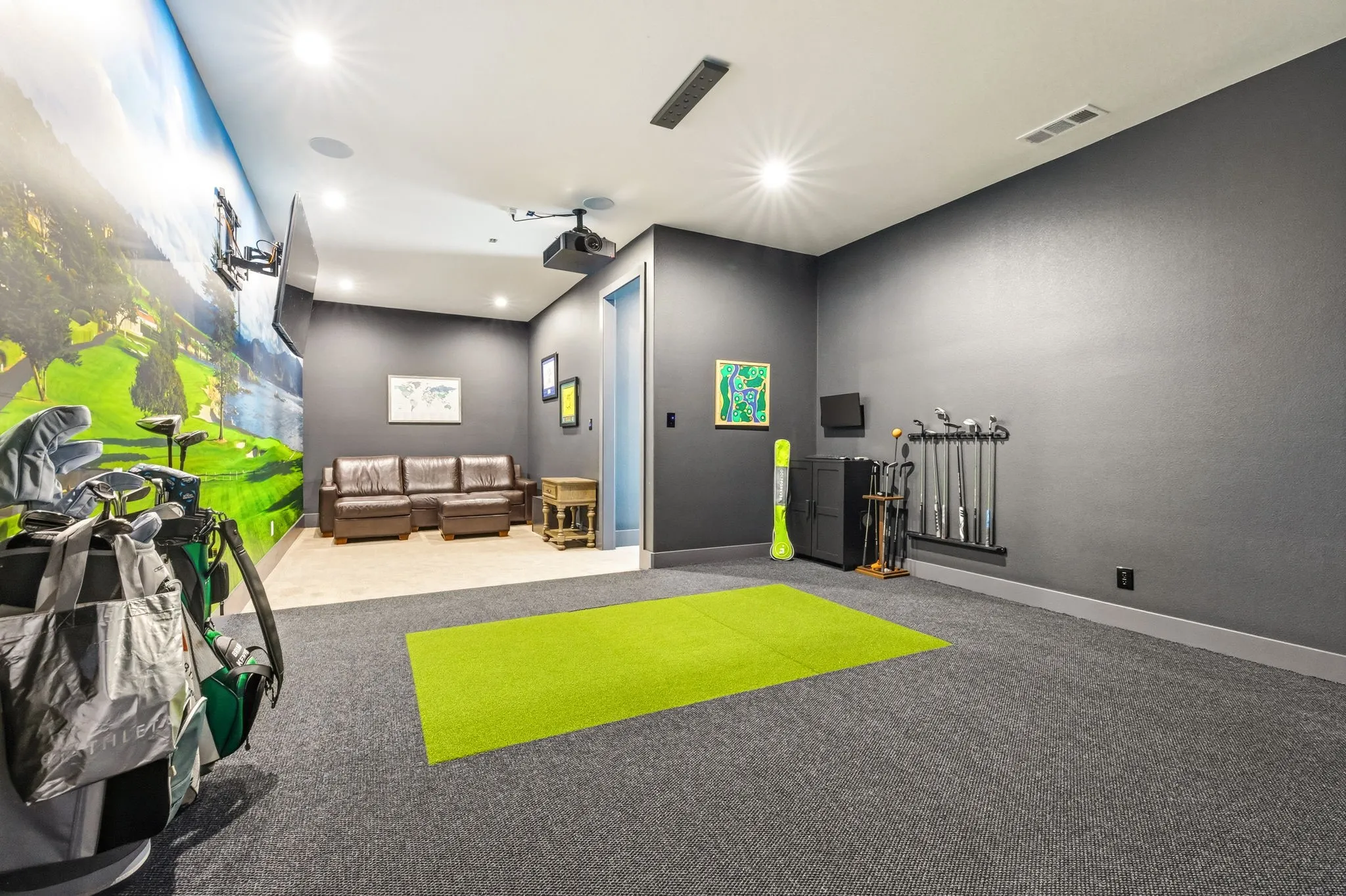 Recessed lighting, wall-mounted projector, wall-mounted display, golf-themed wall mural, and carpeted flooring with a putting mat