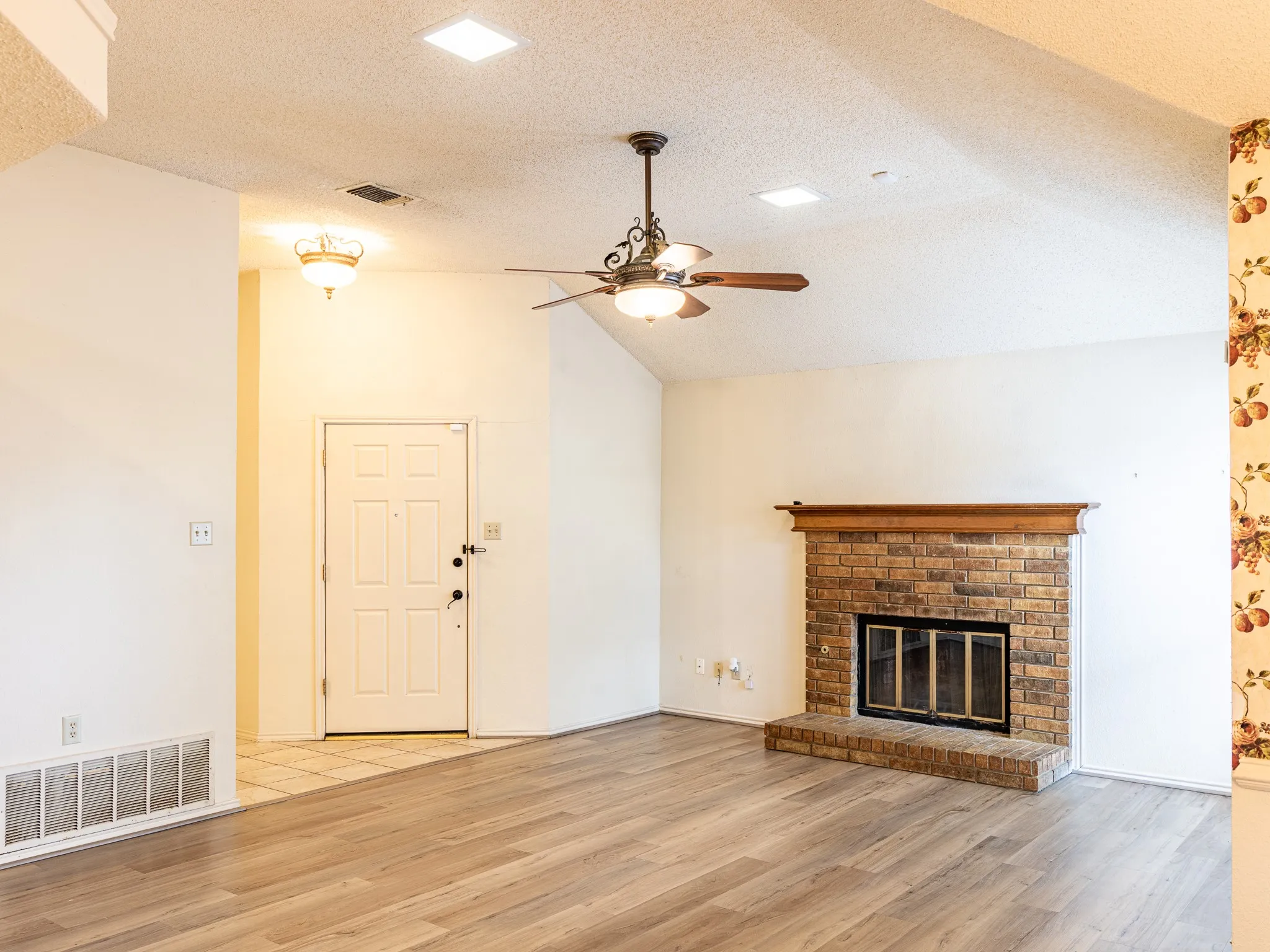 Vaulted ceiling with a ceiling fan, brick fireplace, wood-finish flooring, and recessed lighting
