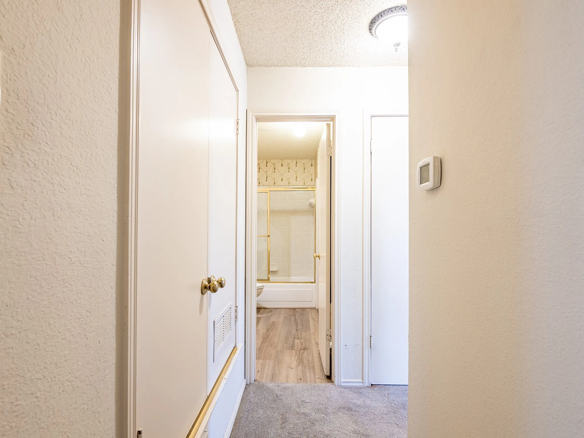 Carpeted hallway with painted walls, recessed lighting, and a white interior door