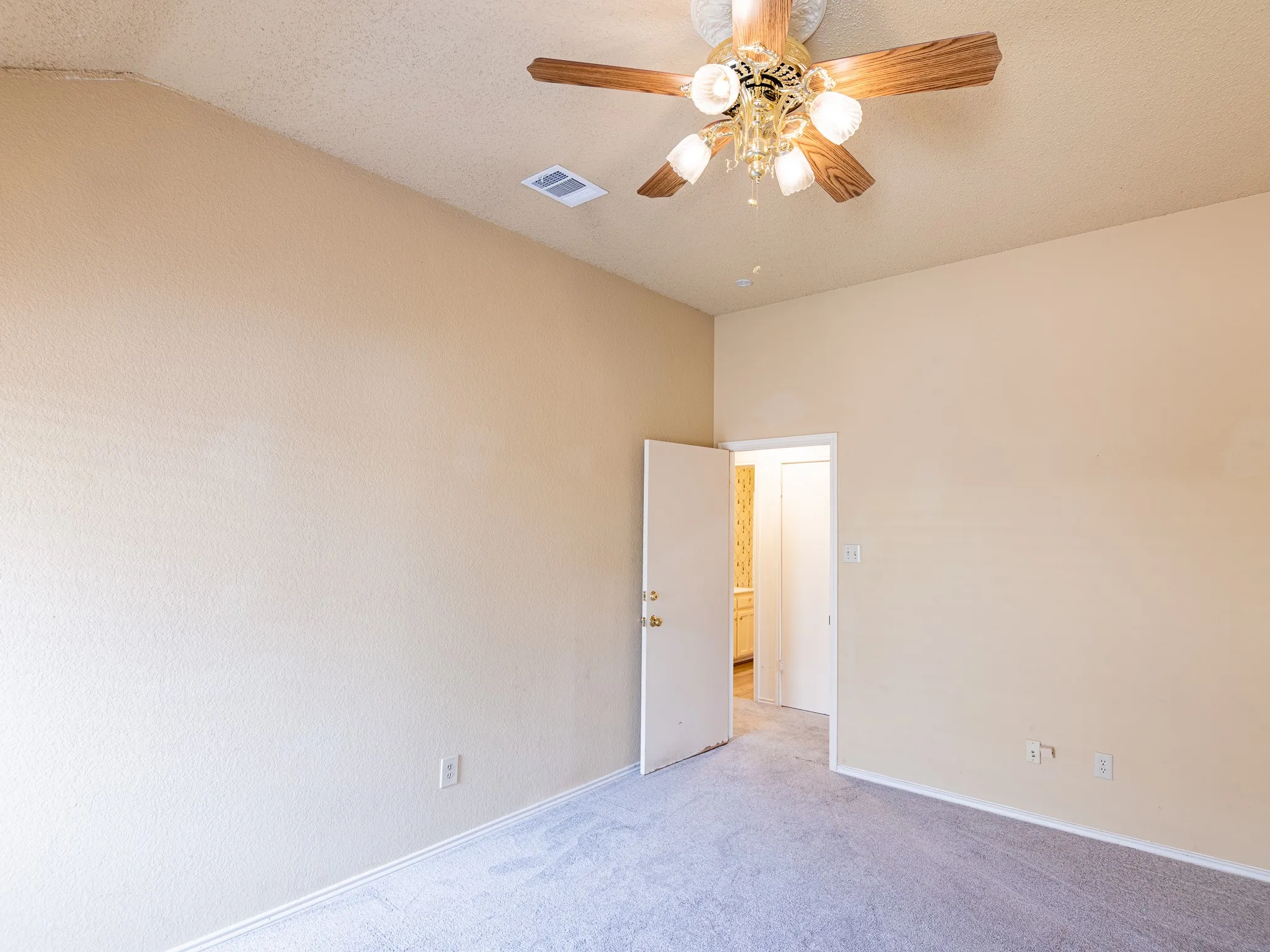 Textured walls, light-colored carpeting, and a ceiling fan with light fixture