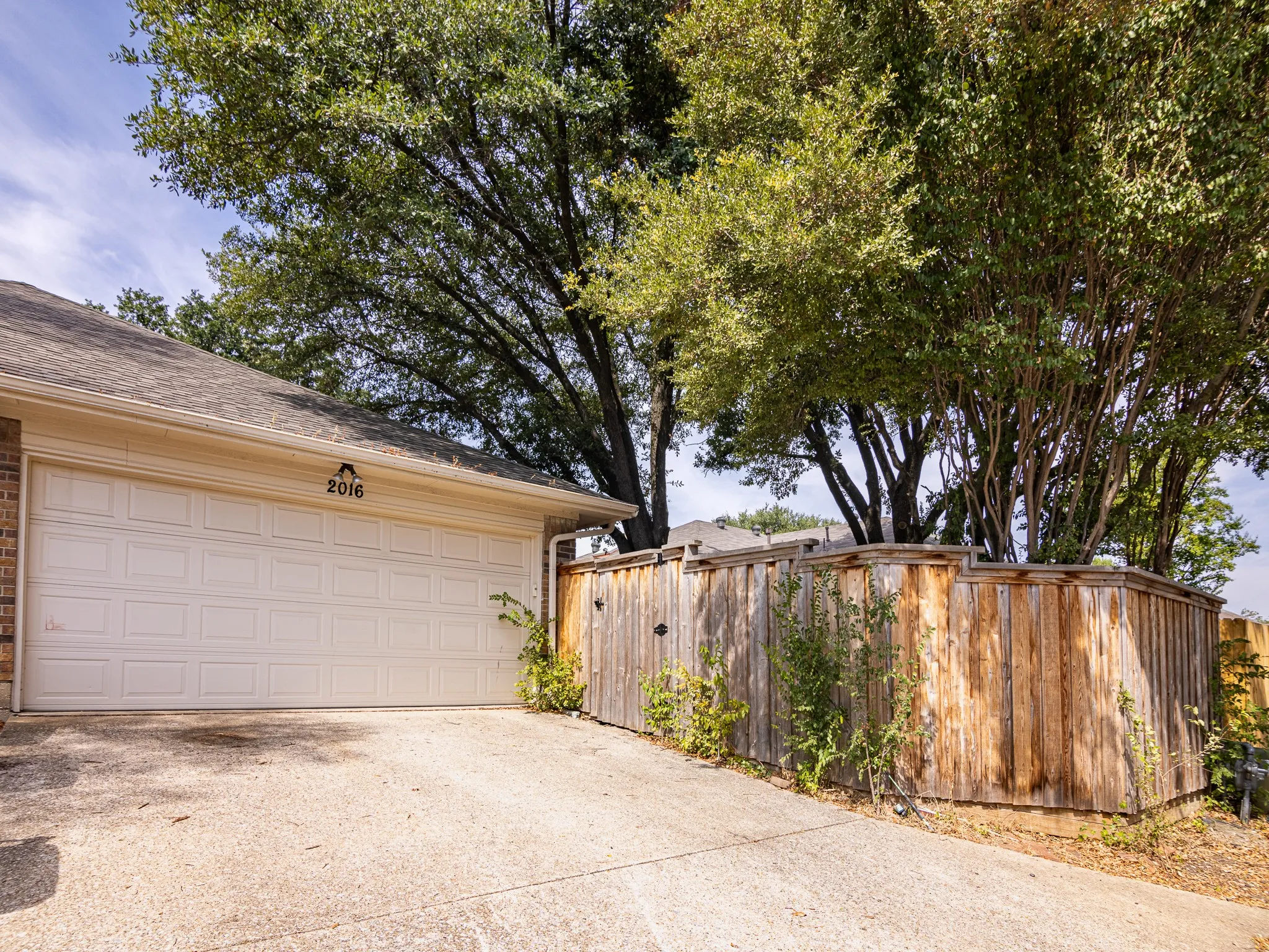 Two-car garage with panel-style doors, concrete driveway, and wood privacy fencing