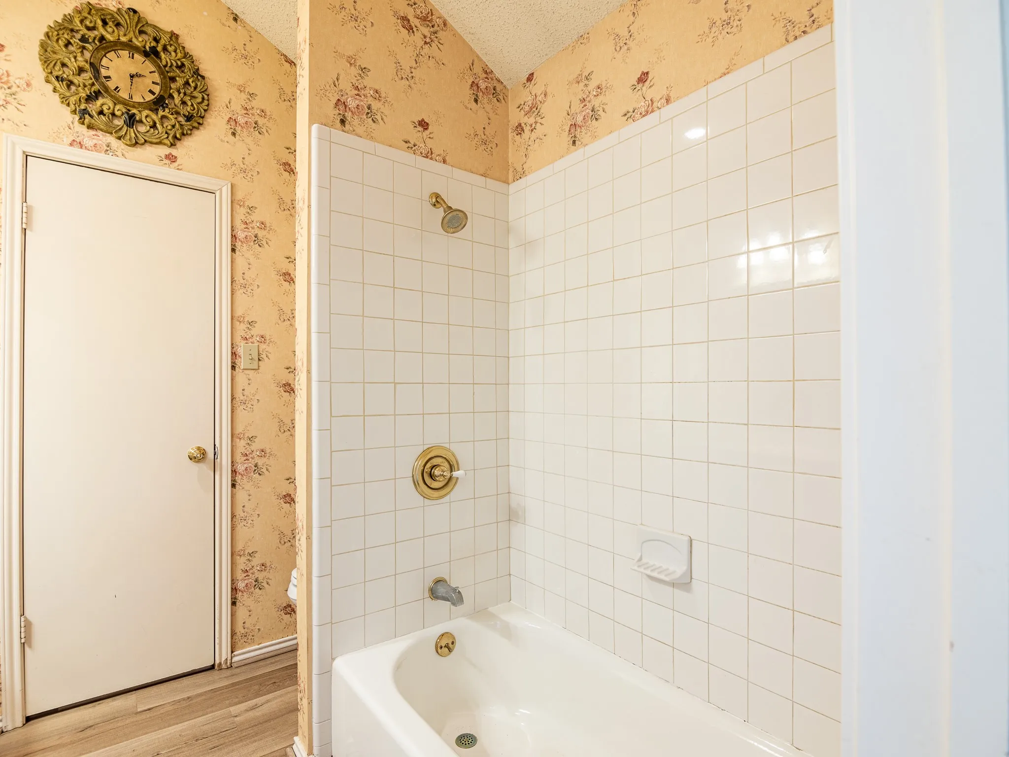 White tiled shower and tub combination featuring brass fixtures