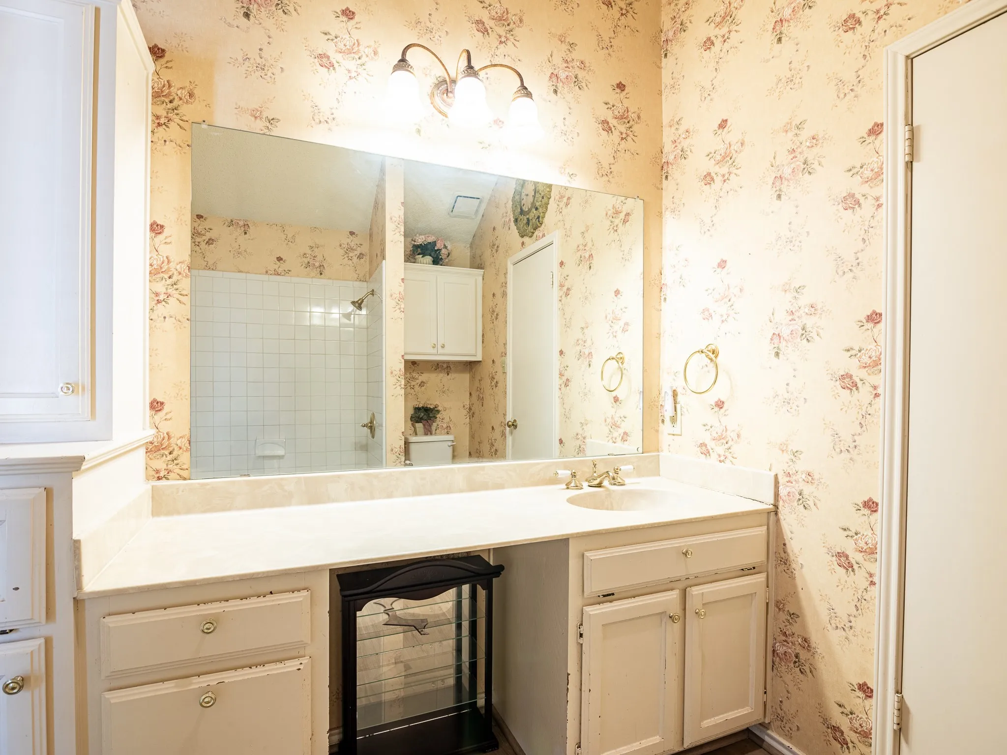 Built-in vanity with a single basin, a large mirror, and an overhead three-light fixture